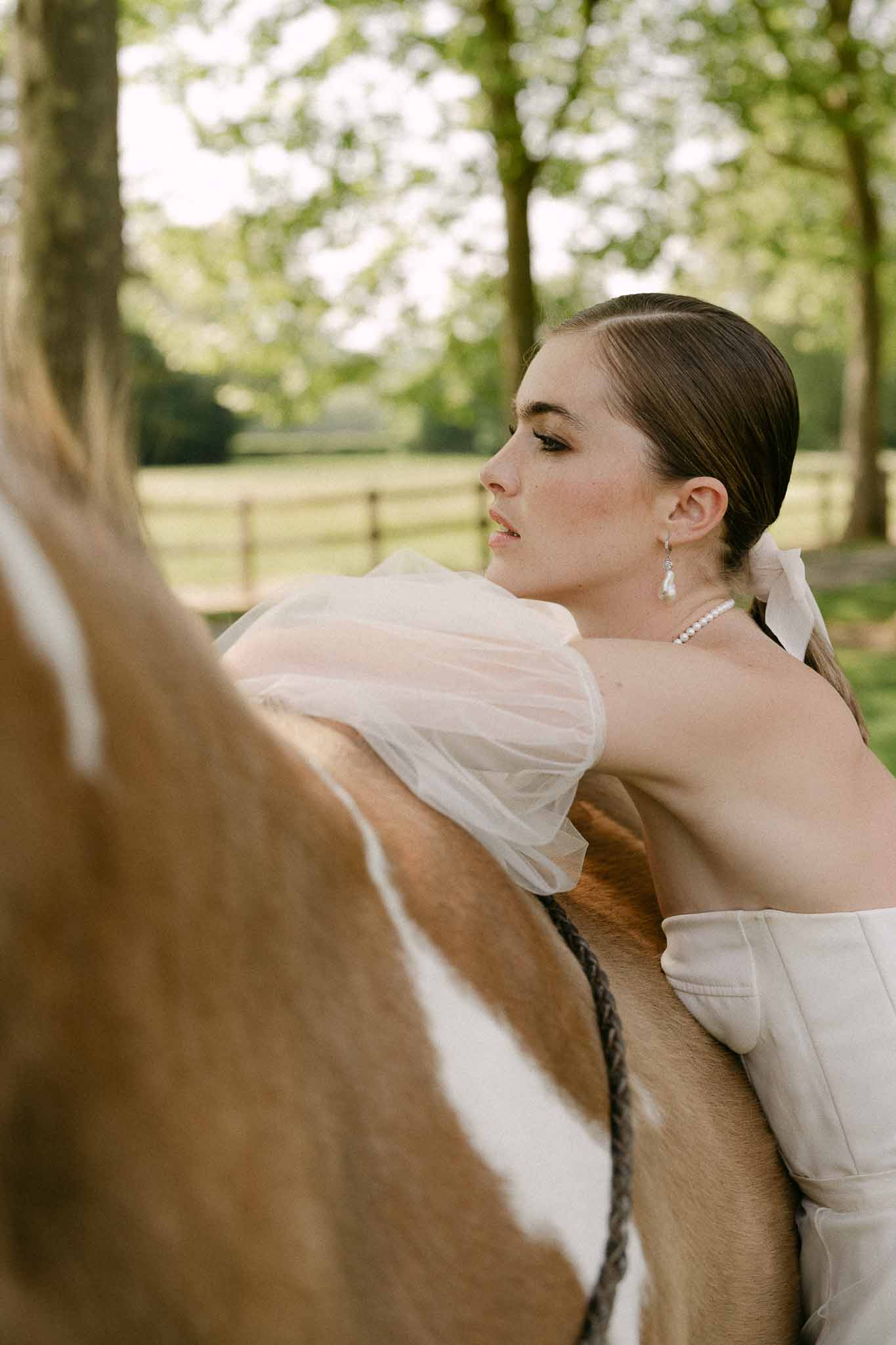 Bride in ivory gown with pearl jewelry in garden setting during wedding portrait session