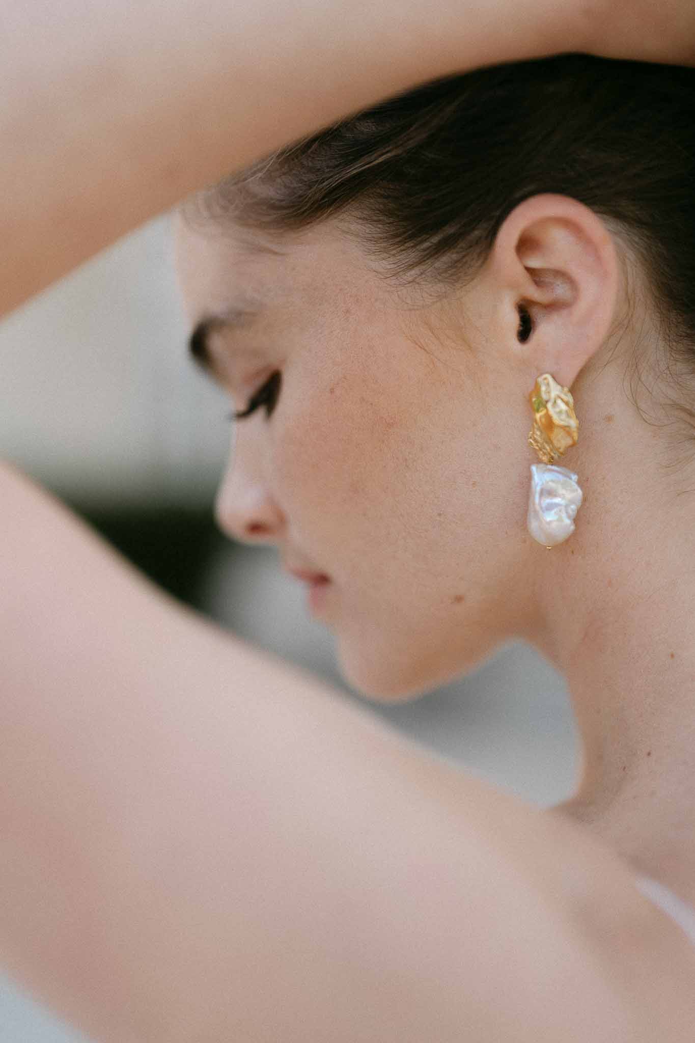 Close-up of bride's baroque pearl drop earrings and profile at wedding venue