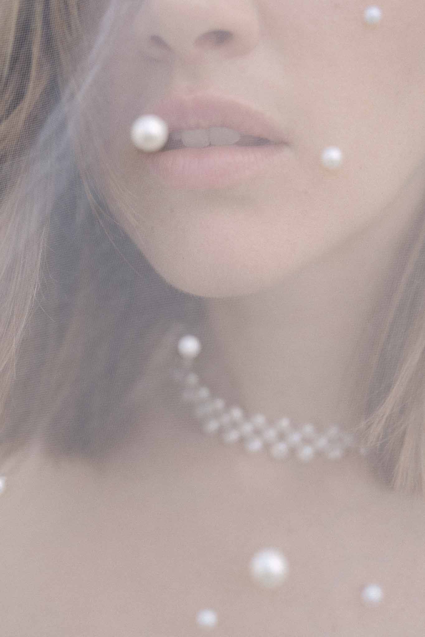 Bride wearing pearl necklace and veil in soft-focus profile portrait