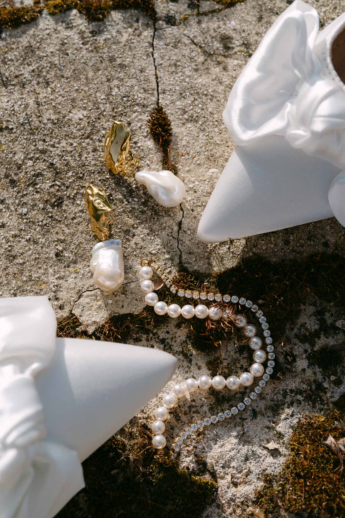 Bridal jewelry flat lay with pearl bracelet and earrings on stone surface
