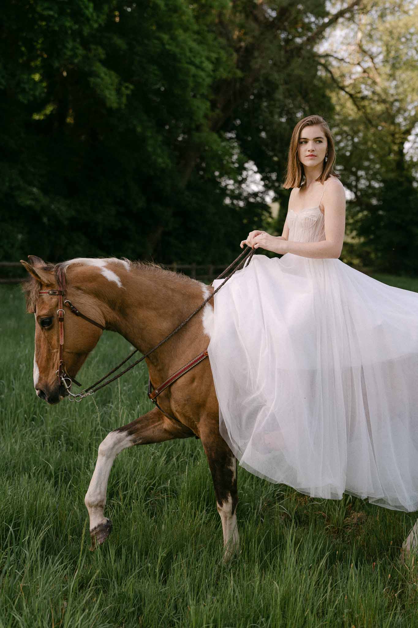 Bride on horseback in garden setting wearing ivory wedding dress with tulle skirt