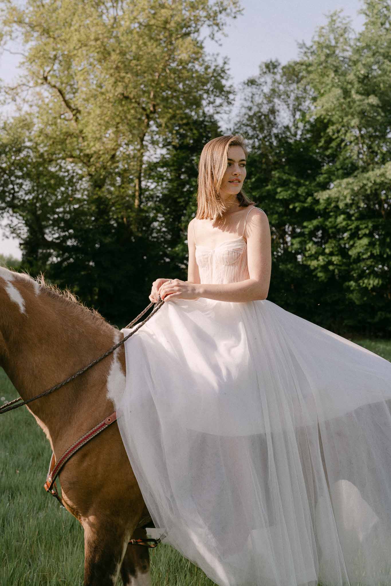 Bride on horseback in wedding dress at outdoor garden venue
