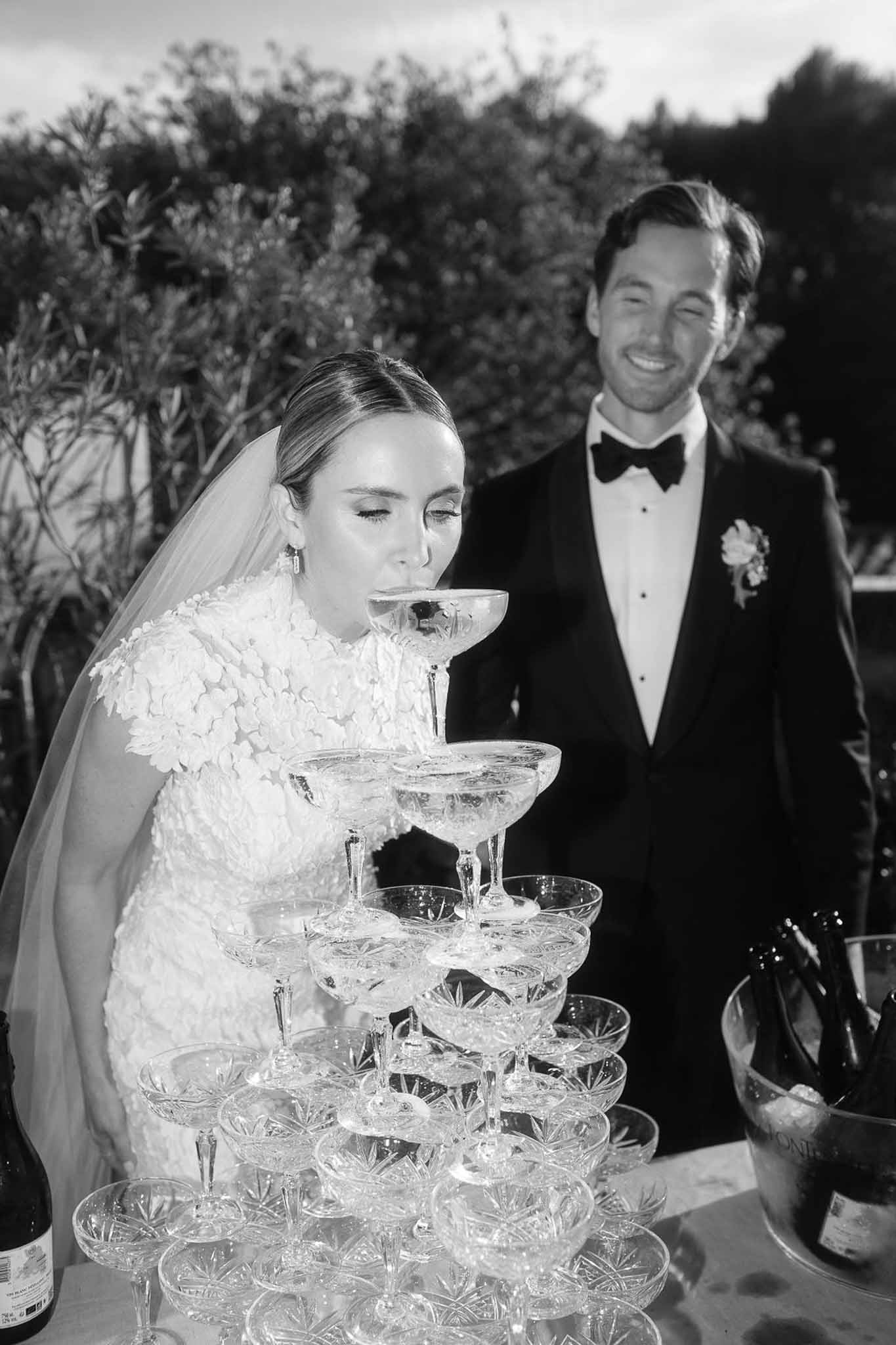 Bride and groom at champagne tower during outdoor wedding reception in formal garden setting