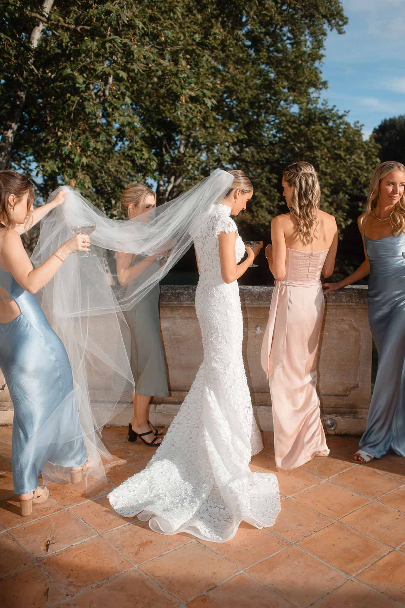 Bride with bridesmaids in pastel dresses on terracotta terrace in Mediterranean garden setting