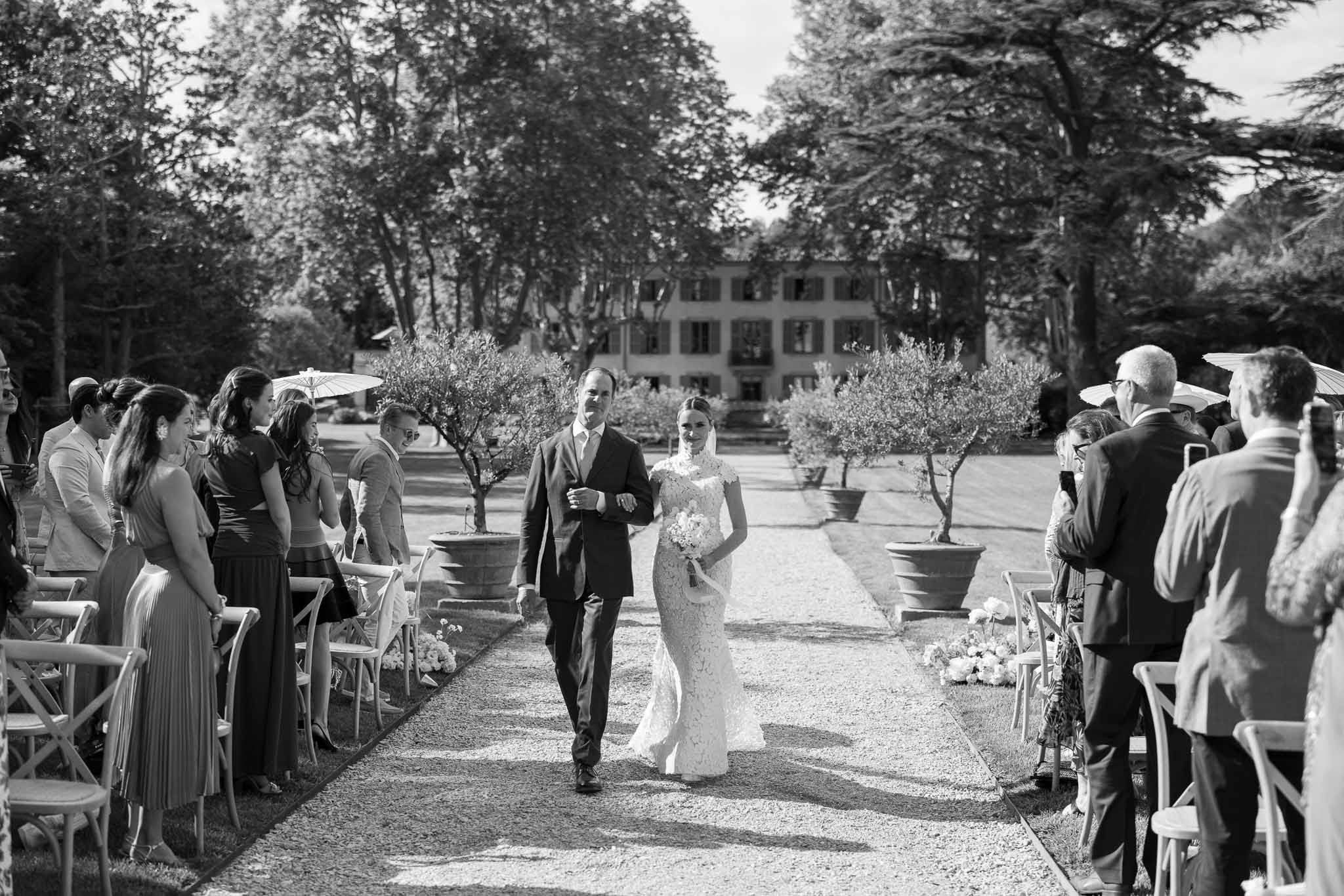 Wedding ceremony recessional at Italian villa courtyard with tree-lined aisle and guests