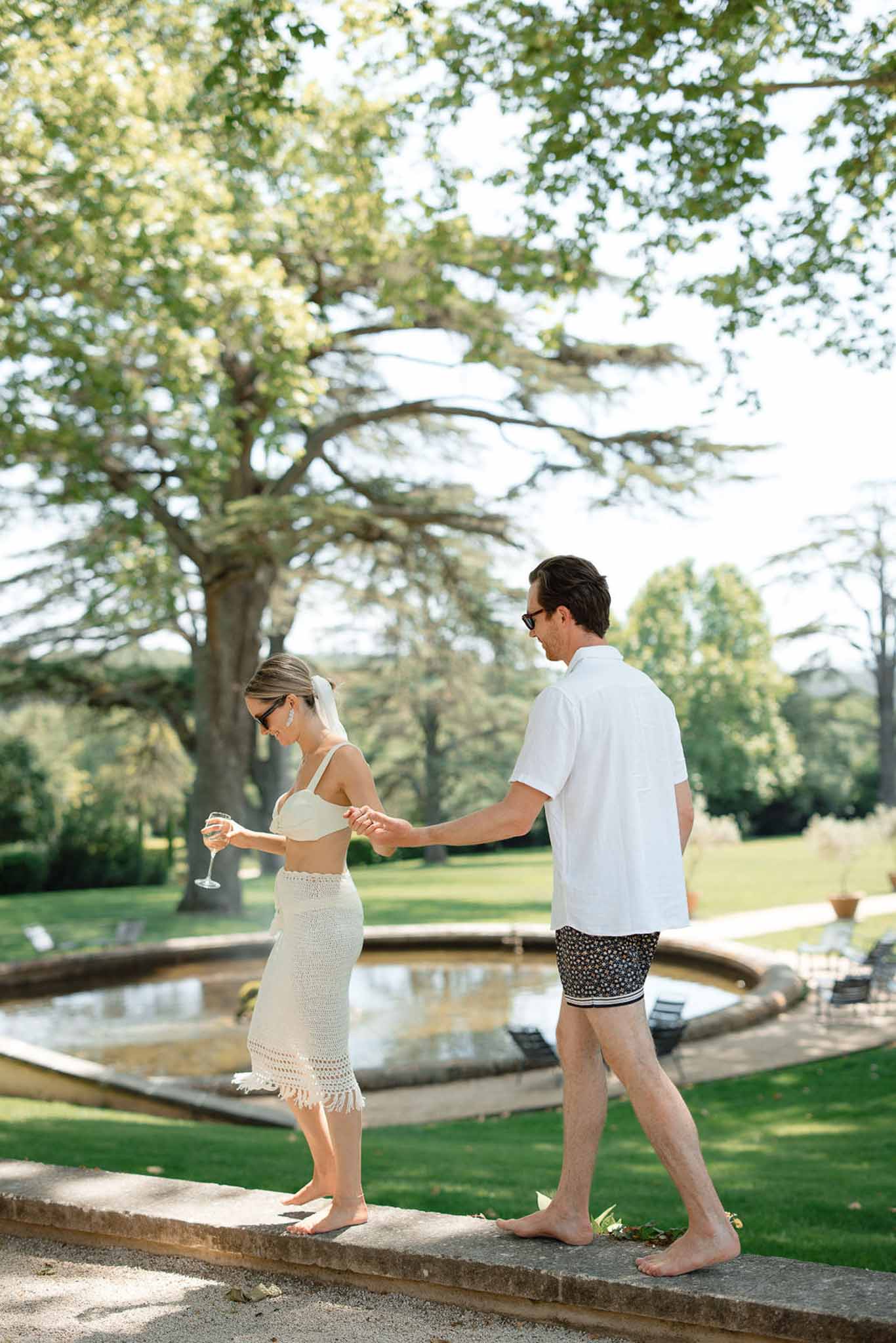 Couple sharing champagne moment by fountain at garden wedding venue