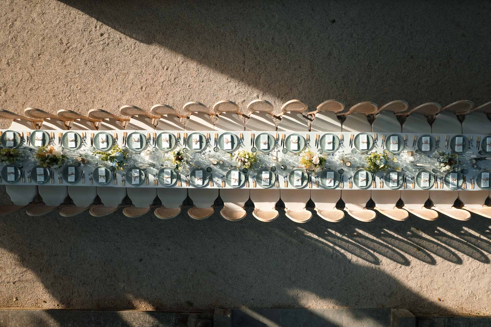 Aerial view of outdoor reception table setting with natural linens and teal napkins