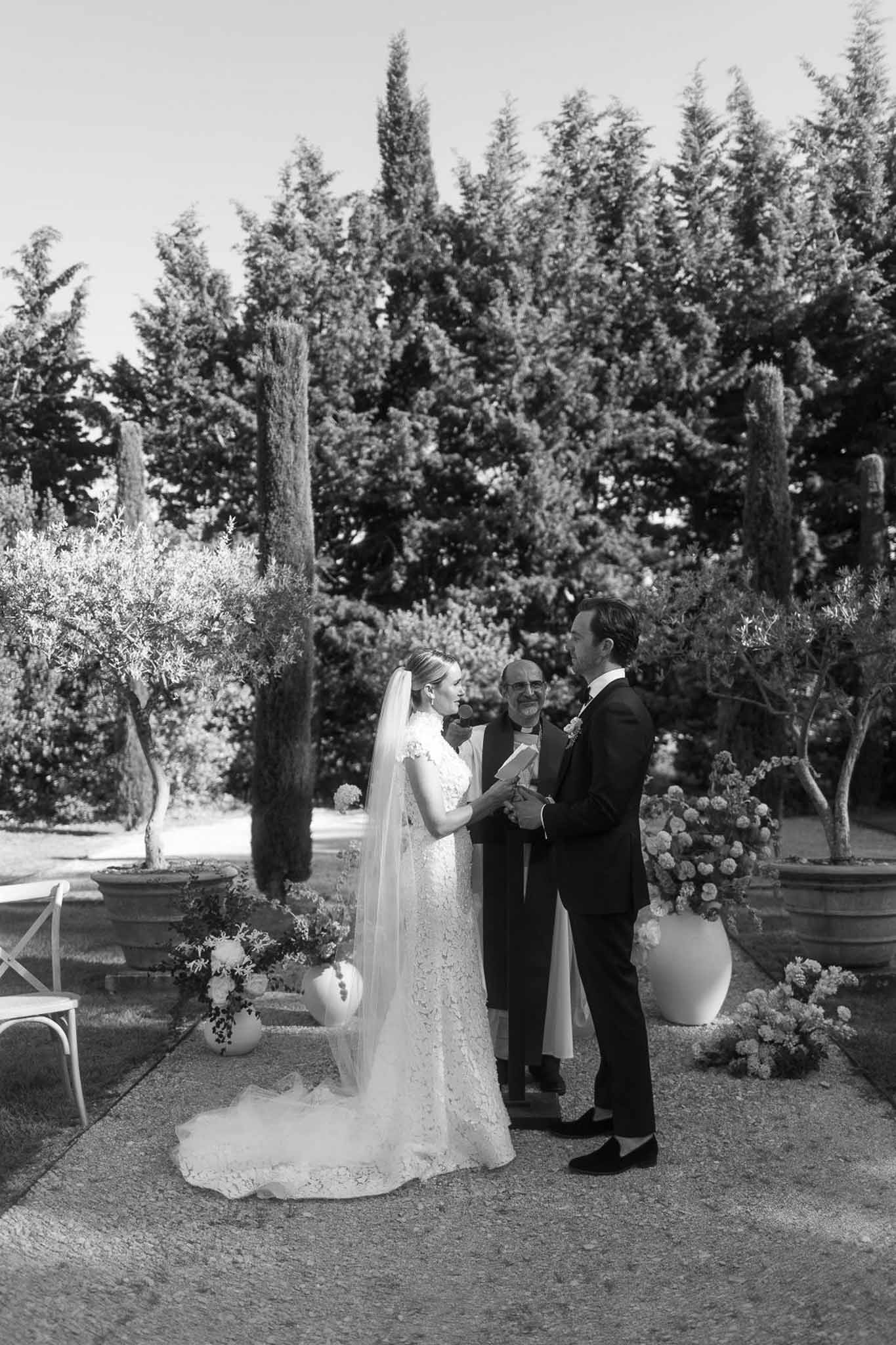 Wedding ceremony with bride and groom exchanging vows in Italian-style garden with cypress trees and terracotta urns