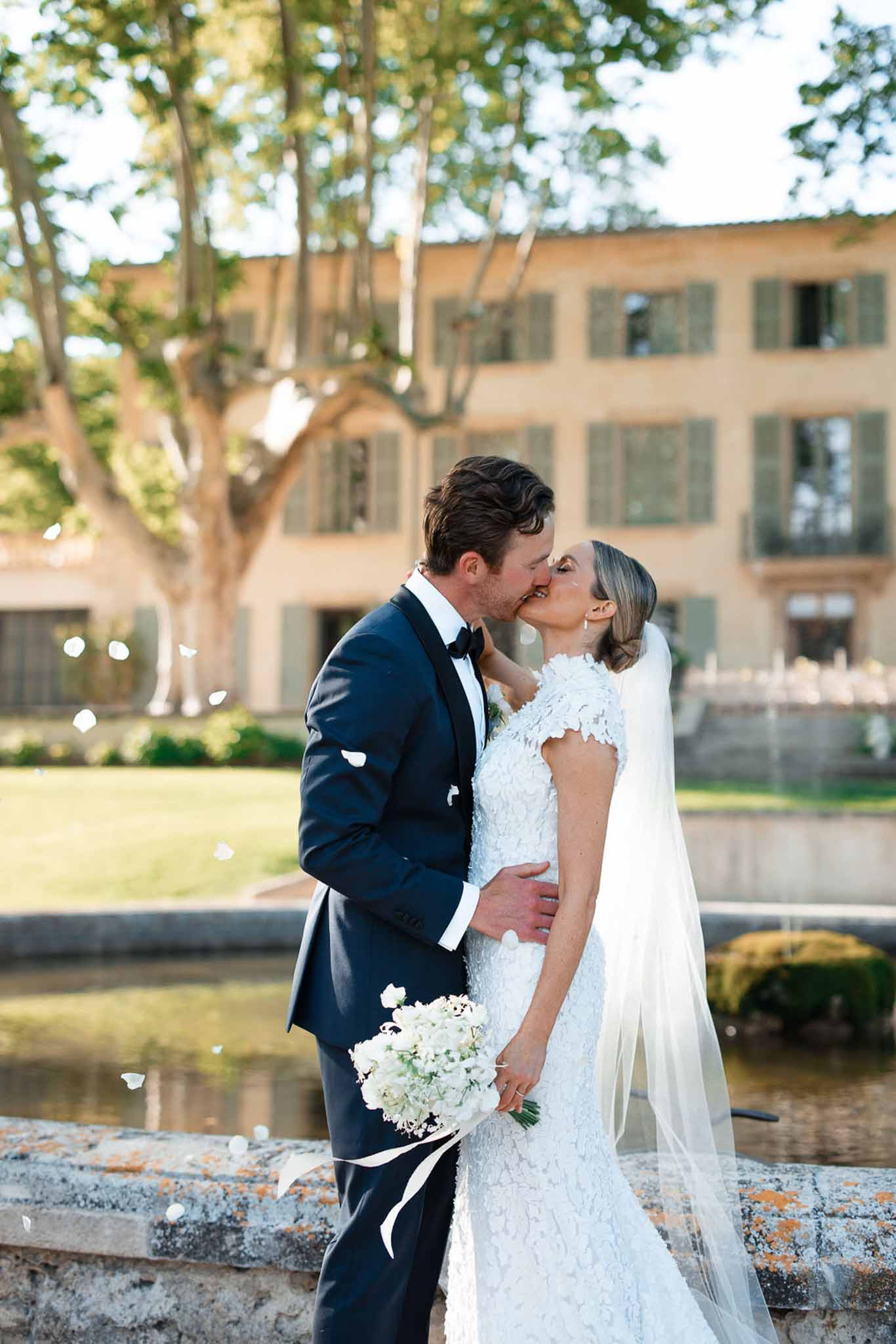 Bride and groom kissing during portraits in historic stone villa courtyard with reflecting pool
