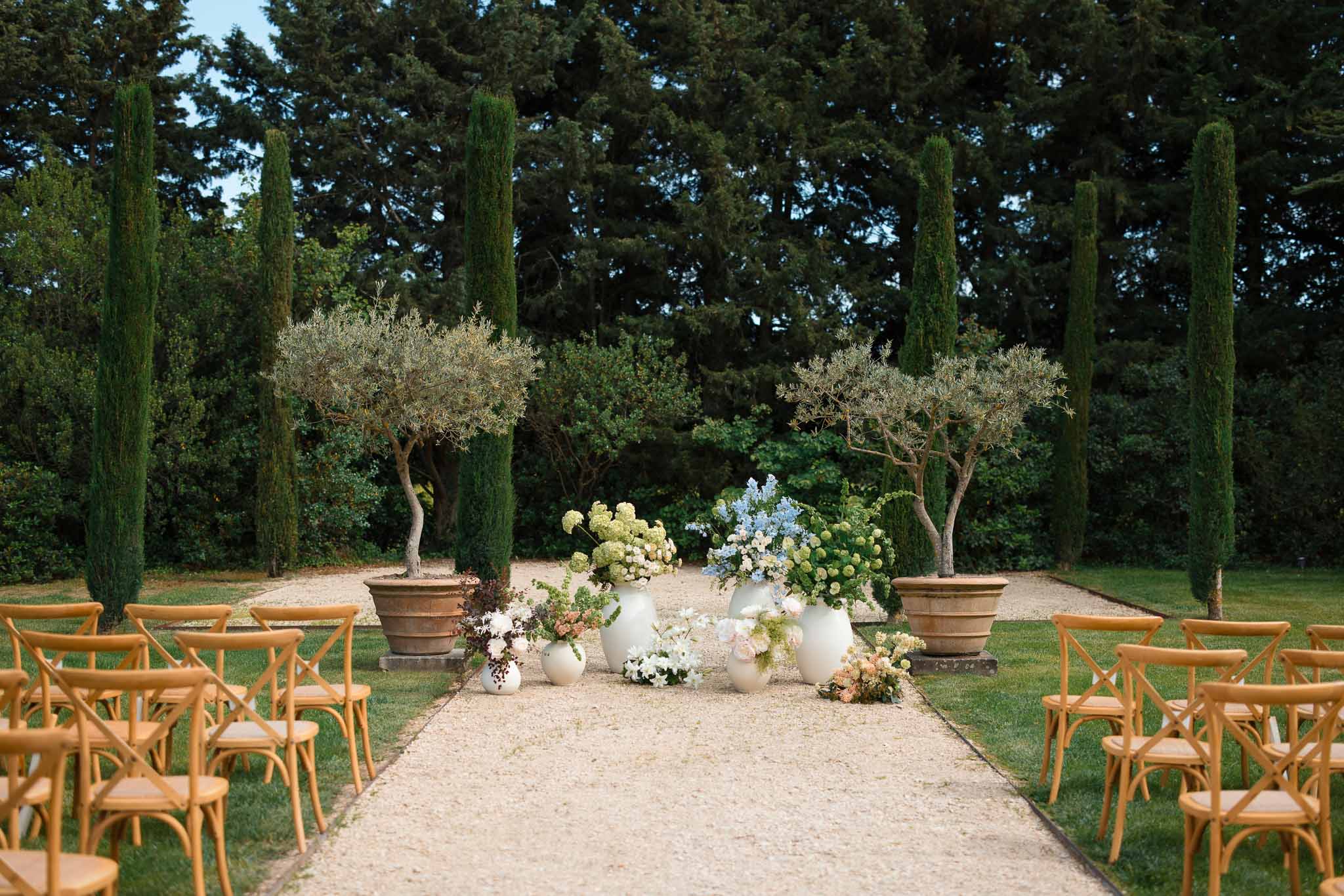 Mediterranean garden ceremony setup with cross-back chairs and hydrangea arrangements at outdoor wedding venue