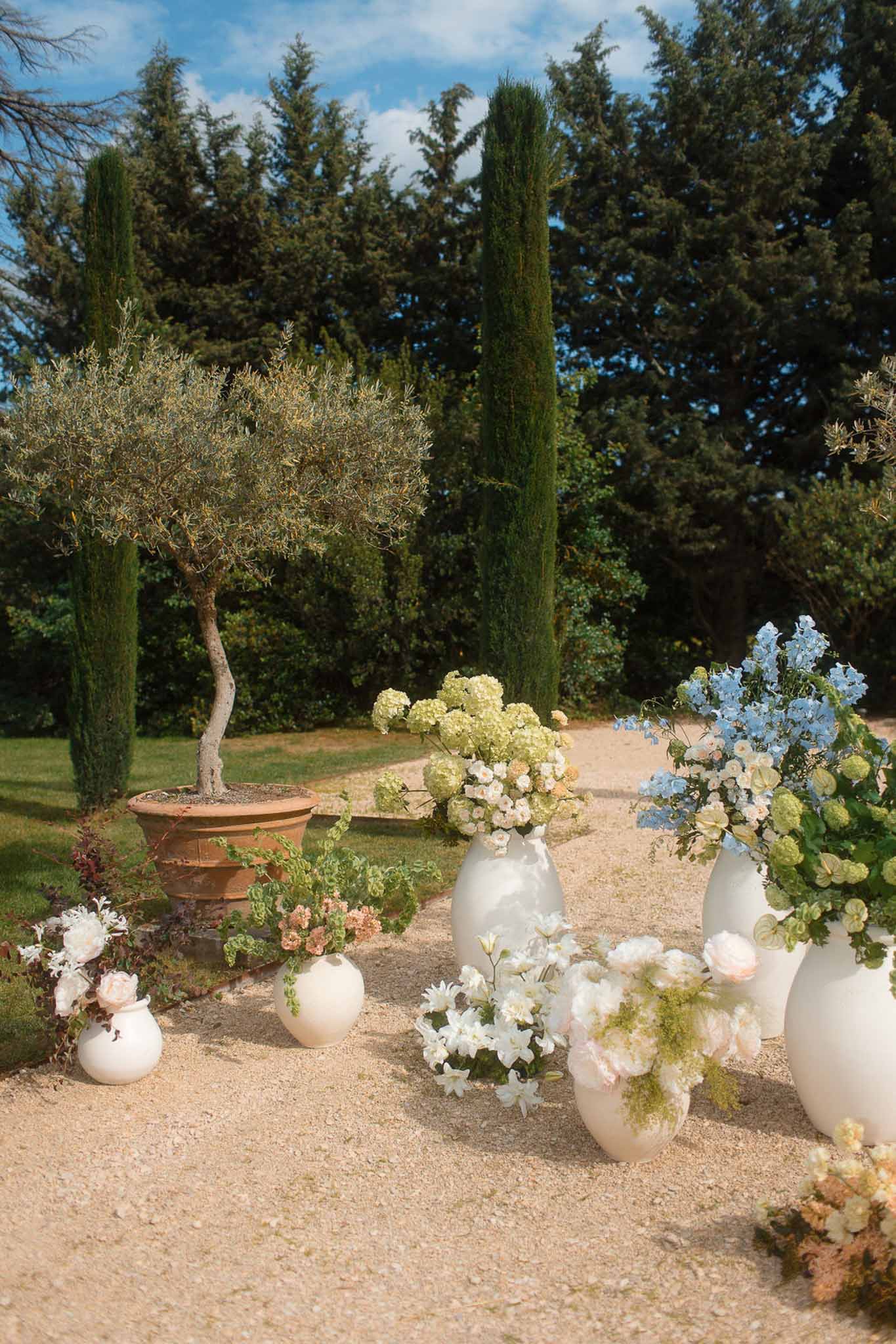 Mediterranean garden wedding ceremony setup with floral arrangements lining gravel pathway