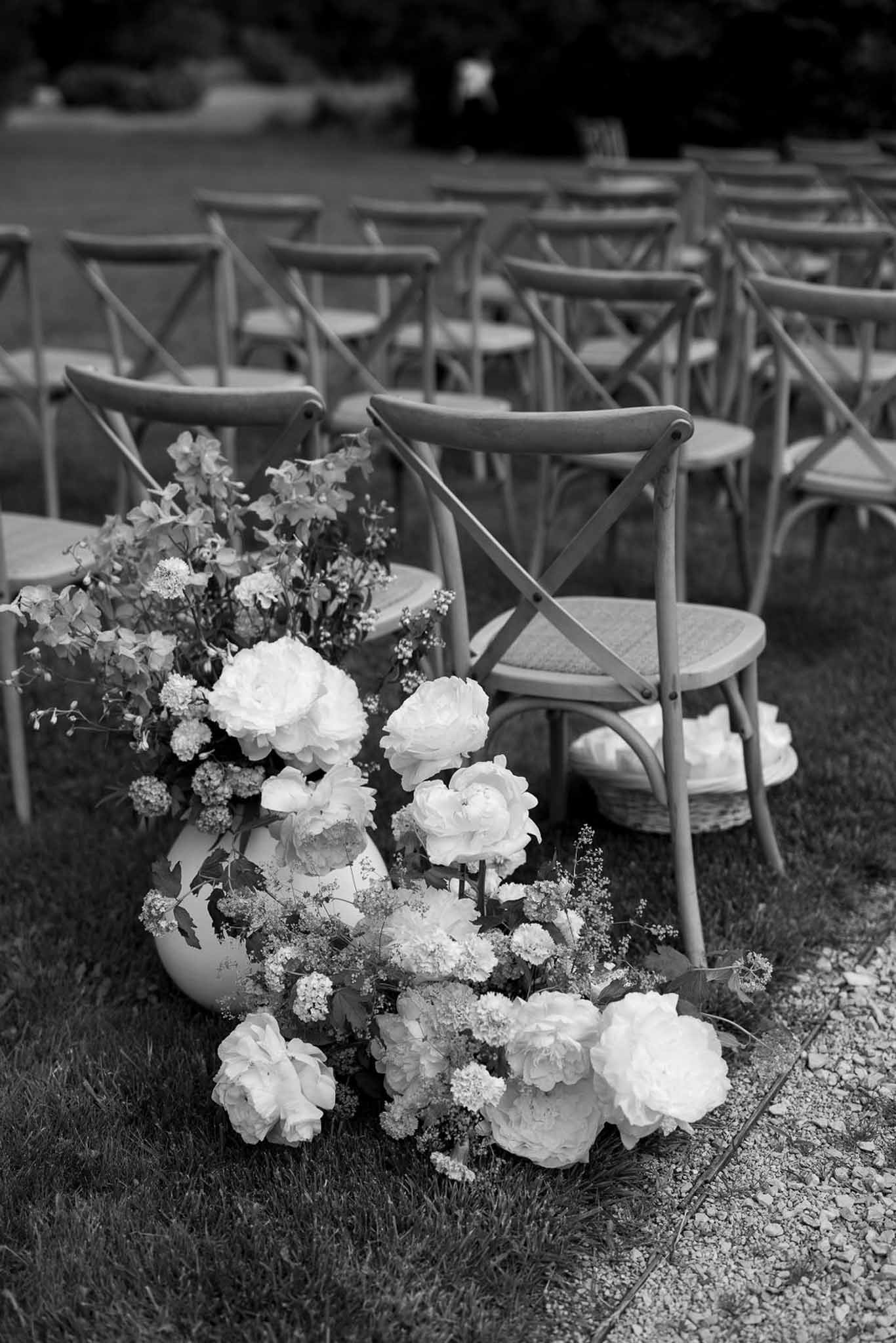 White rose floral arrangement with bentwood chairs at outdoor wedding ceremony