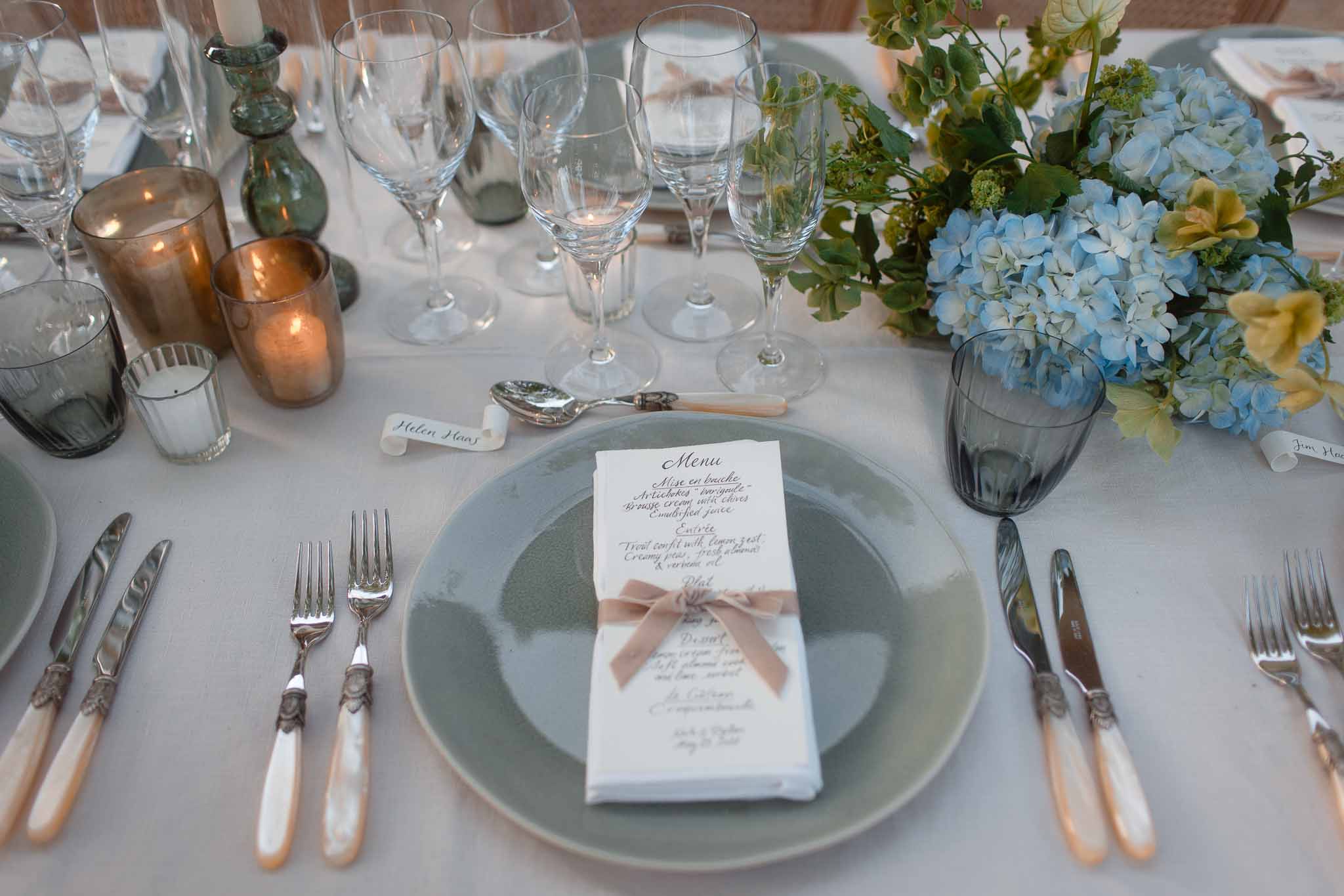 Formal table setting with sage green plates and dusty rose ribbons at wedding reception