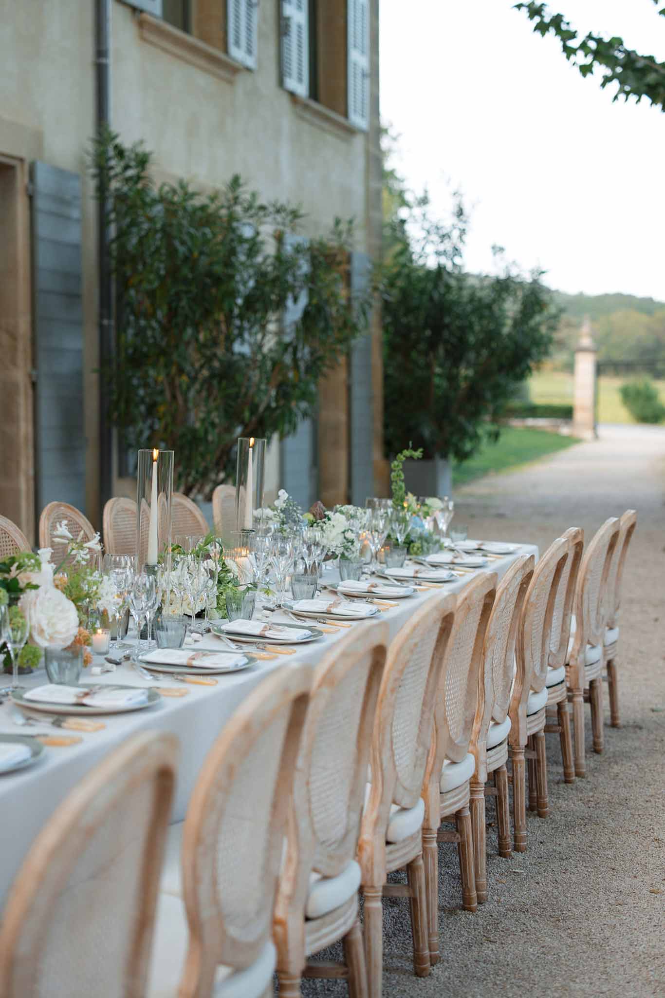 Reception dinner table setup in stone courtyard at Tuscan villa with white florals and countryside views