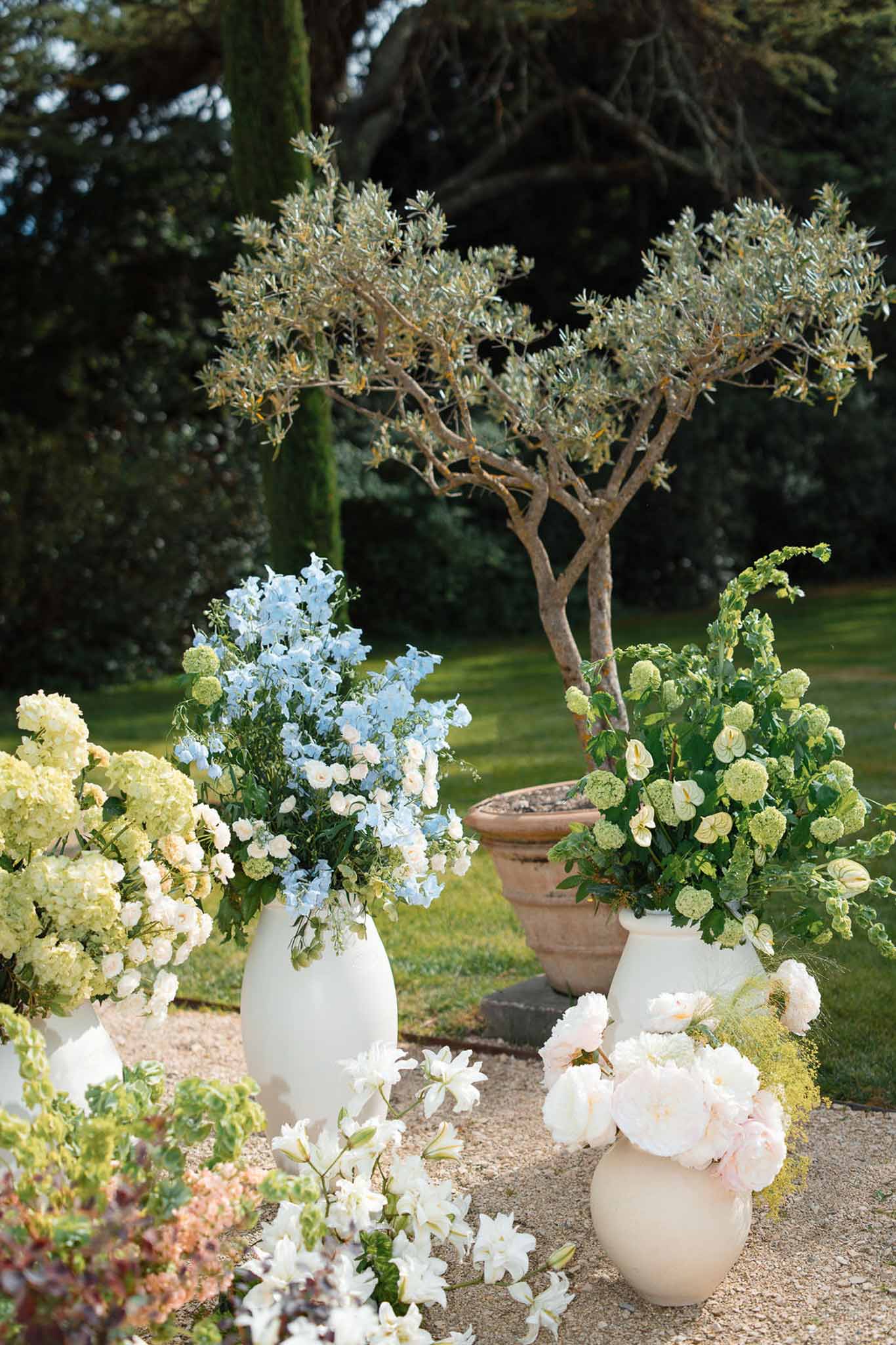 Floral arrangements with hydrangeas and roses along garden pathway at outdoor wedding ceremony