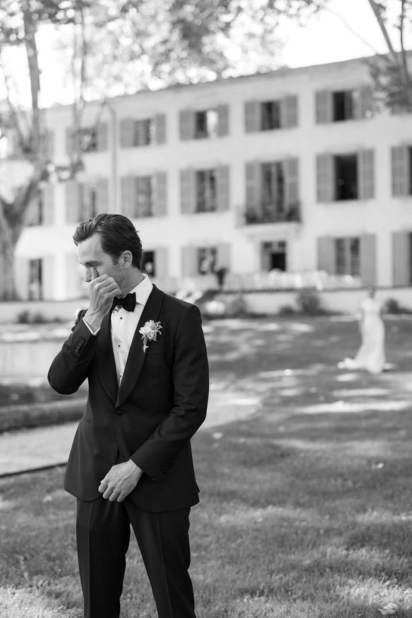 Groom in black tuxedo contemplative portrait at neoclassical courtyard venue