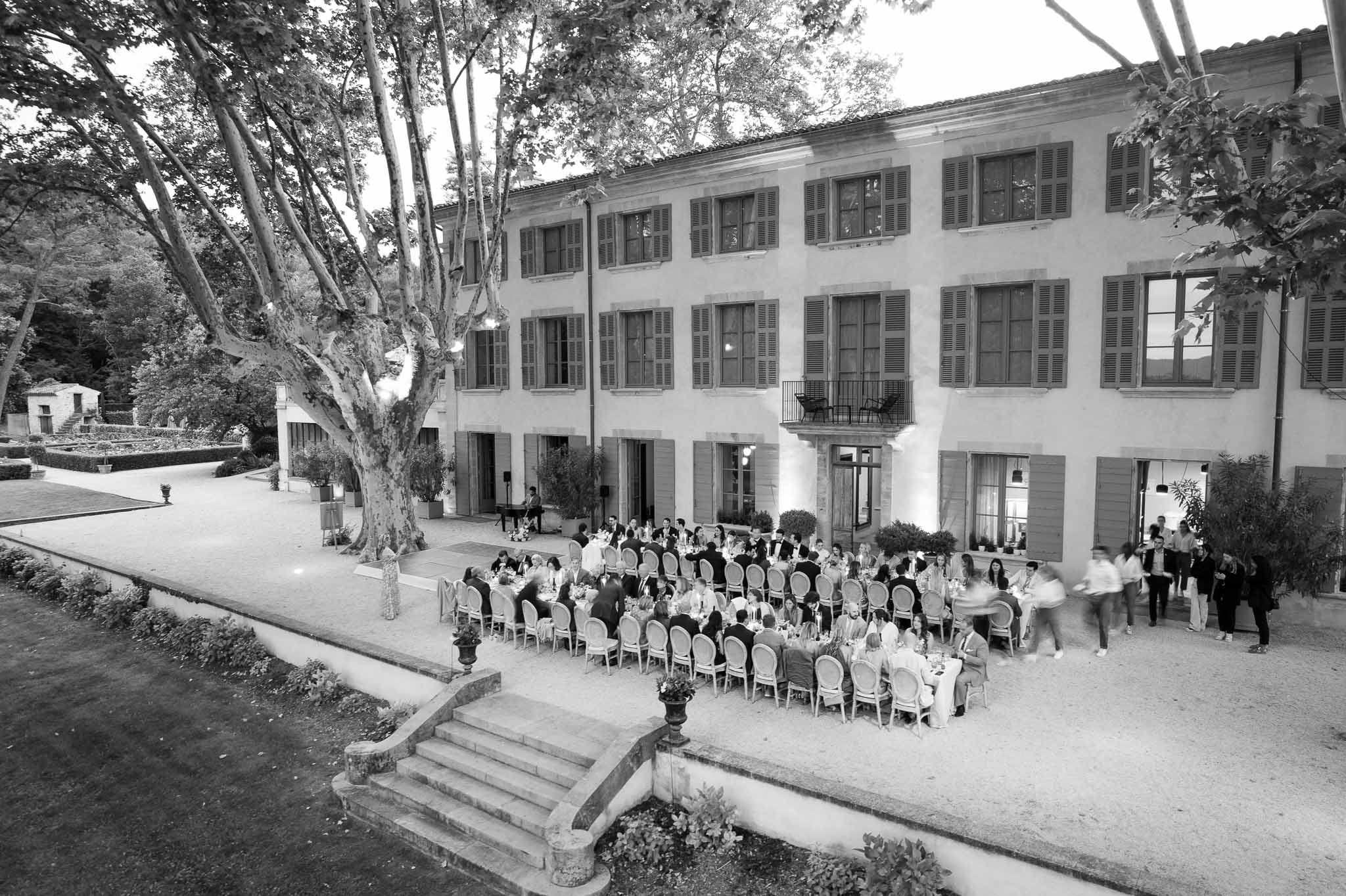 Aerial view of wedding reception dinner in classical mansion courtyard with guests at long tables