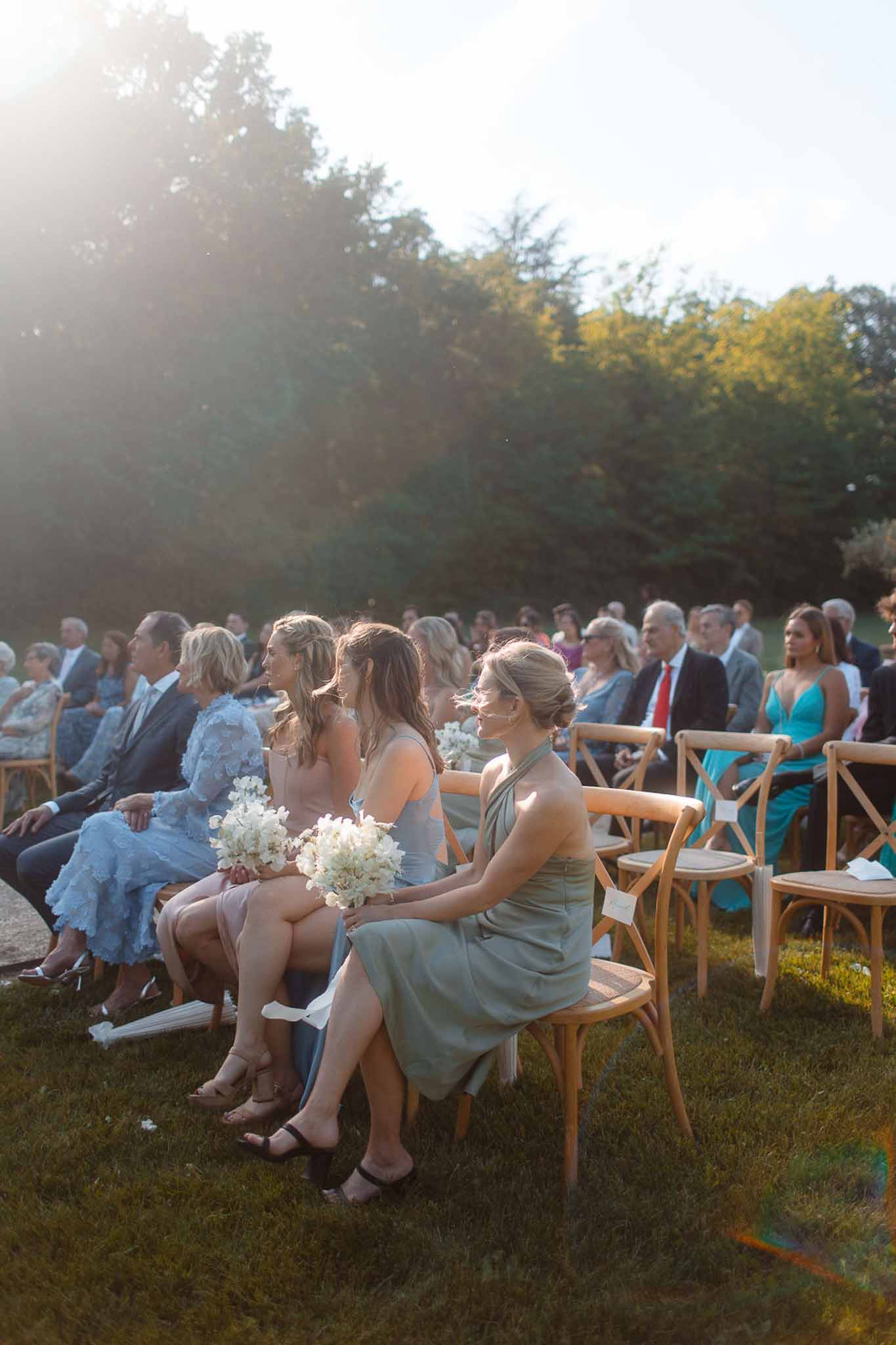 Outdoor wedding ceremony with guests seated in field during golden hour