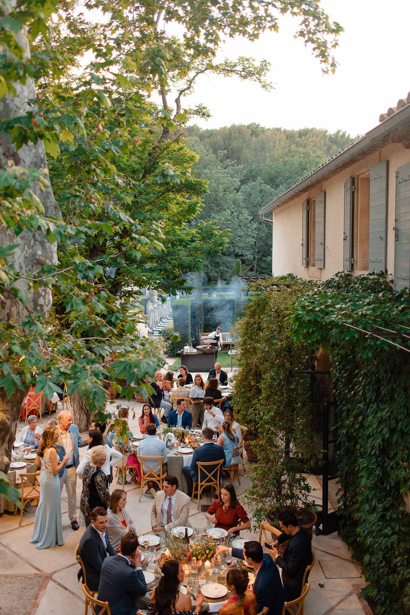 Aerial view of outdoor wedding reception dinner in stone courtyard with ivy-covered walls and round guest tables