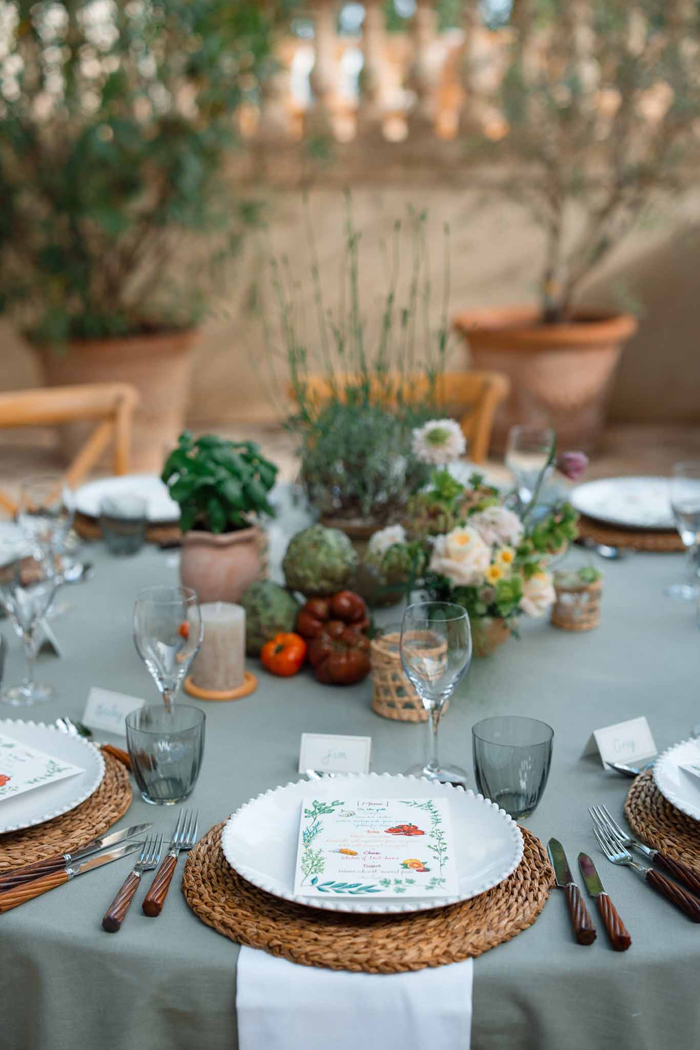Garden-inspired table setting with sage linens and botanical centerpiece at outdoor wedding venue
