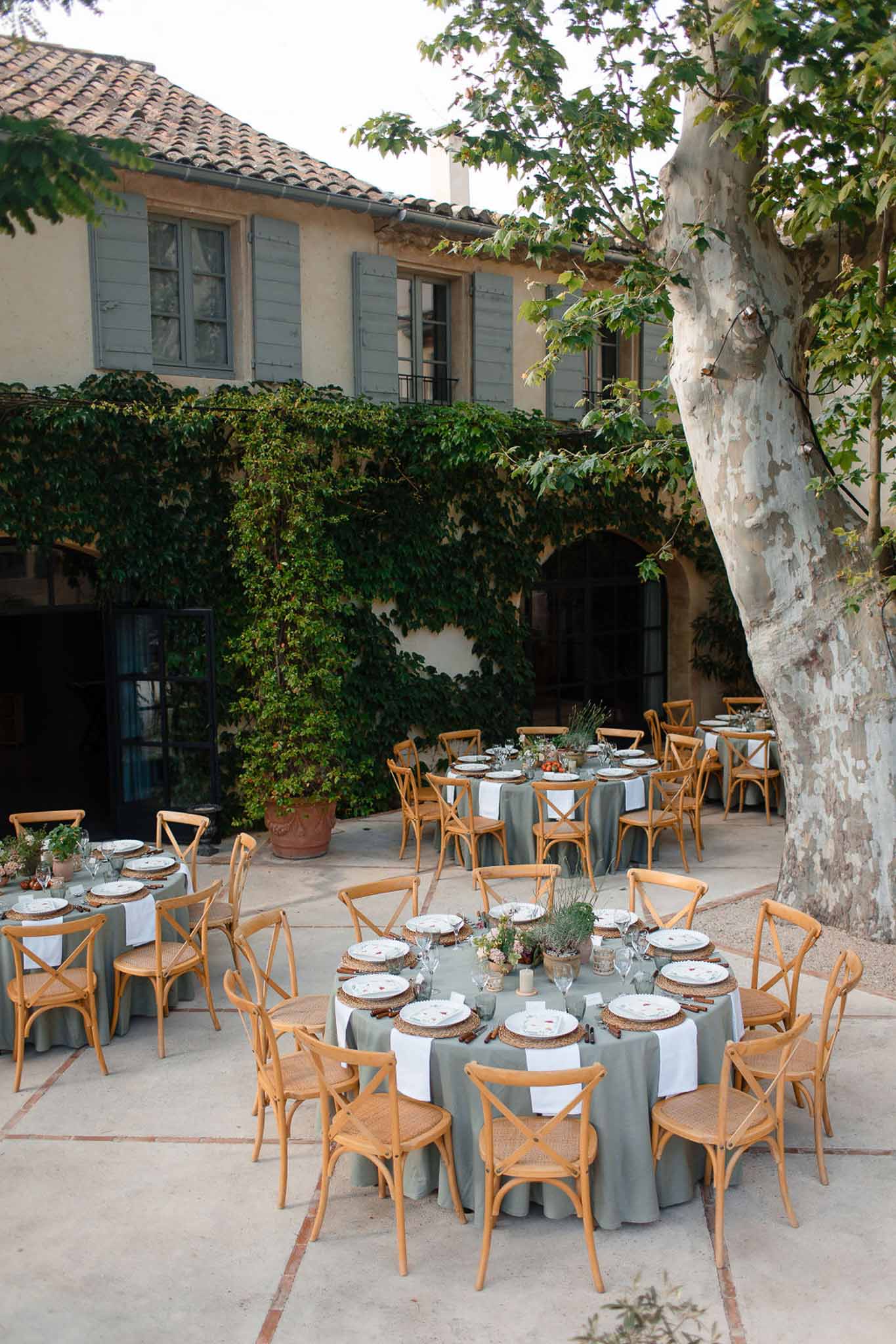 Mediterranean courtyard reception setup with round tables and ivy-covered stone building