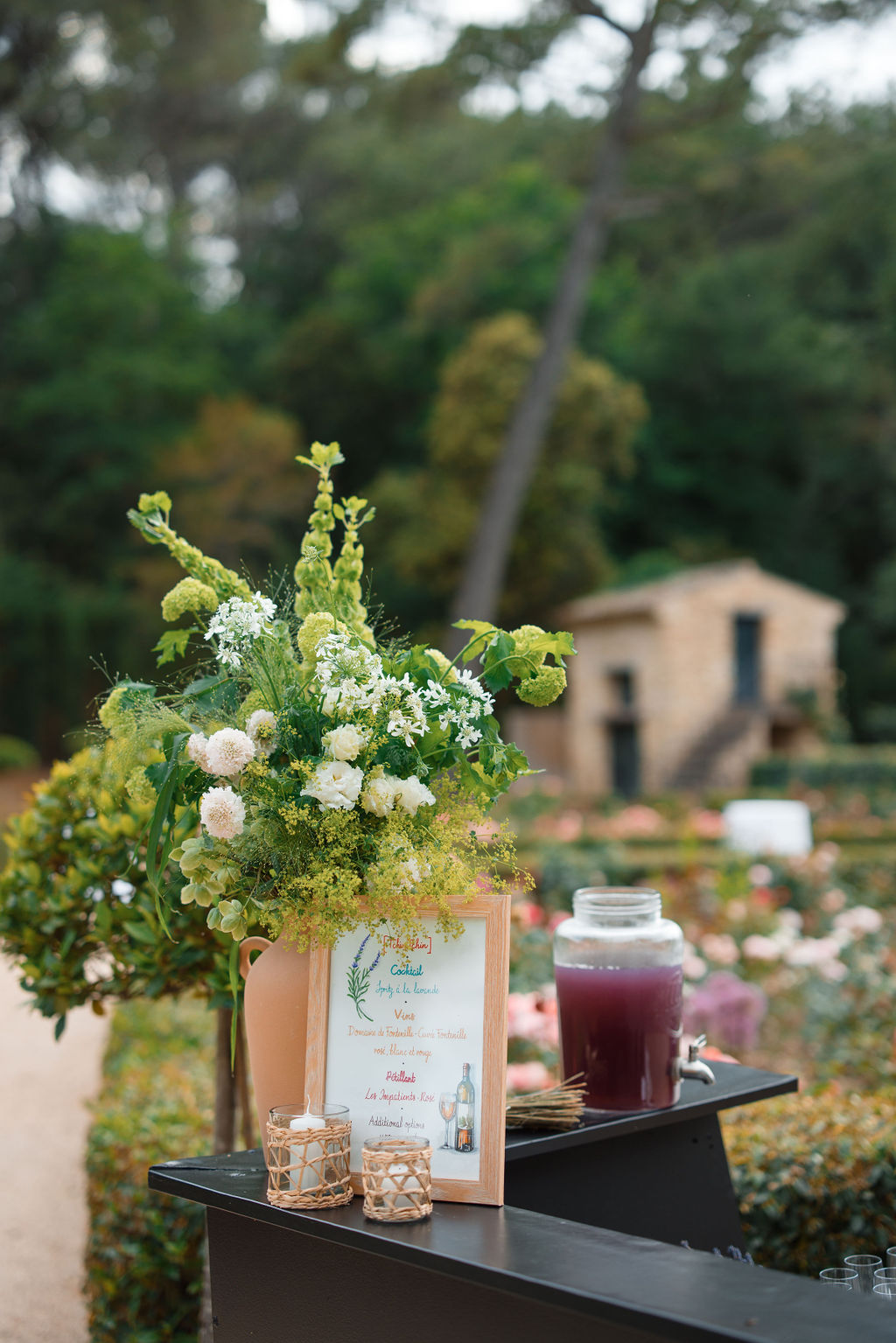 Cocktail hour table setup with white dahlias and menu sign in Mediterranean garden setting