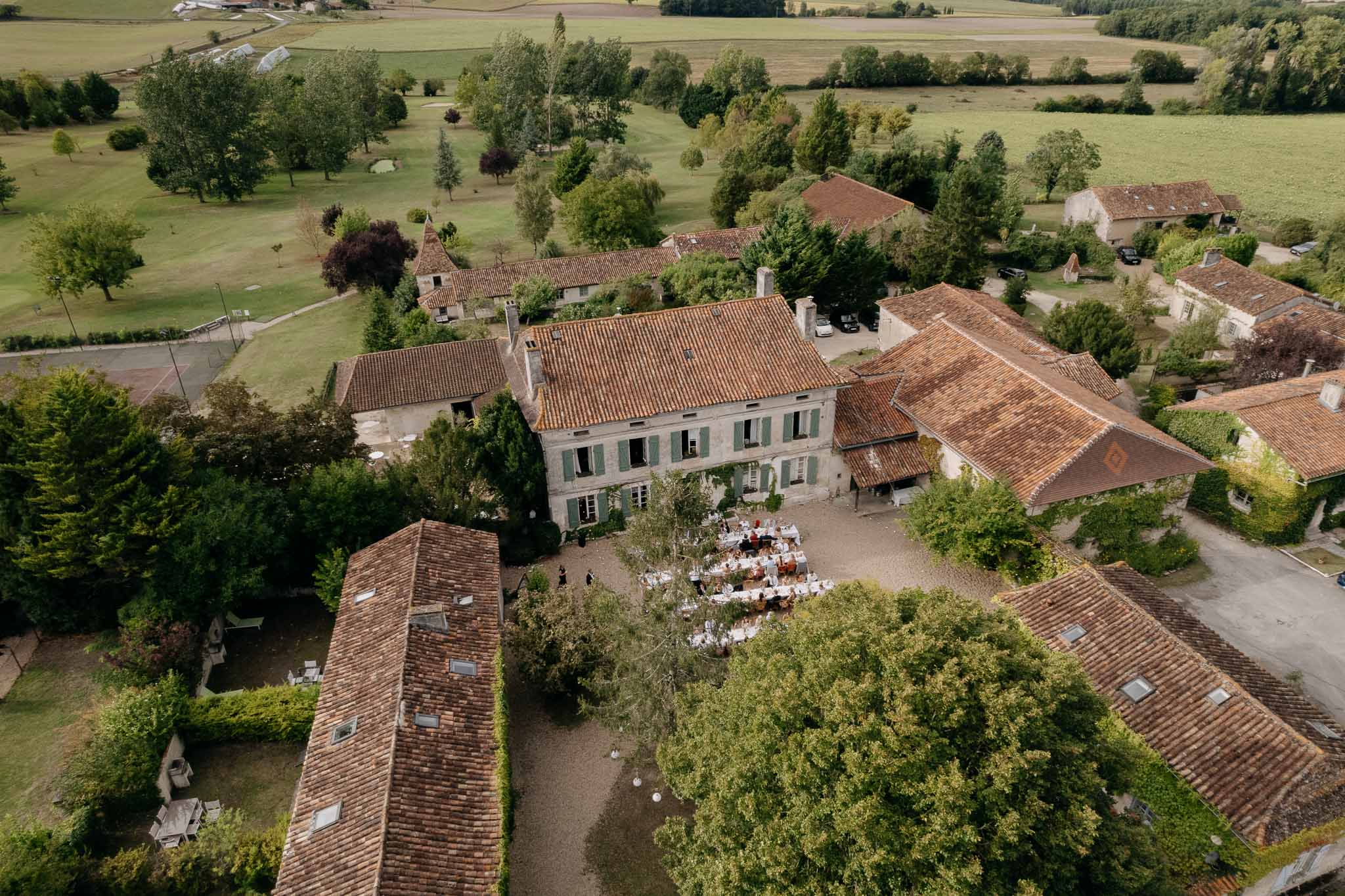 Aerial view of French maison de maitre with teal shutters and courtyard reception from above