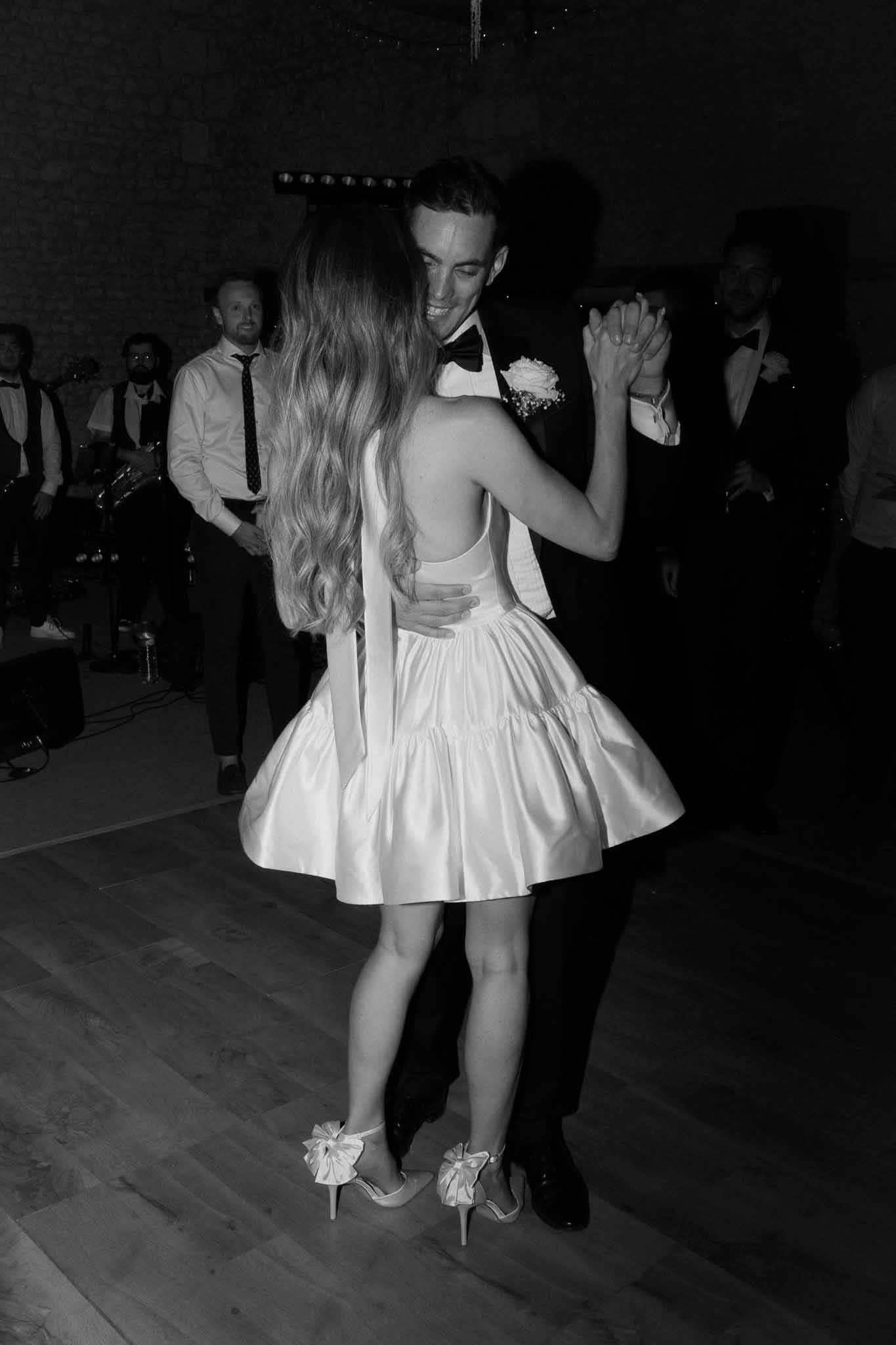 Black-and-white photo of couple sharing their first dance at an indoor stone-walled reception venue