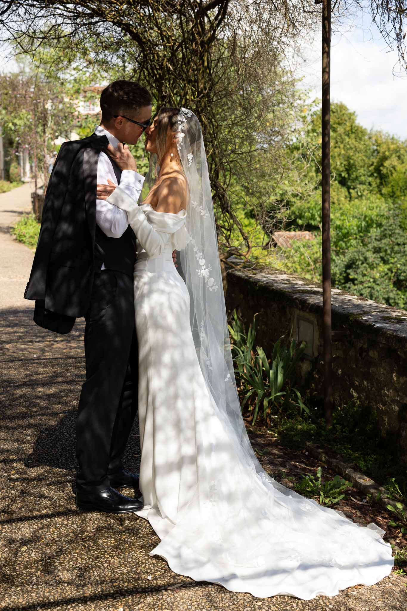 Couple embracing on terrace with bride's floral-applique cathedral veil and puff-sleeve gown