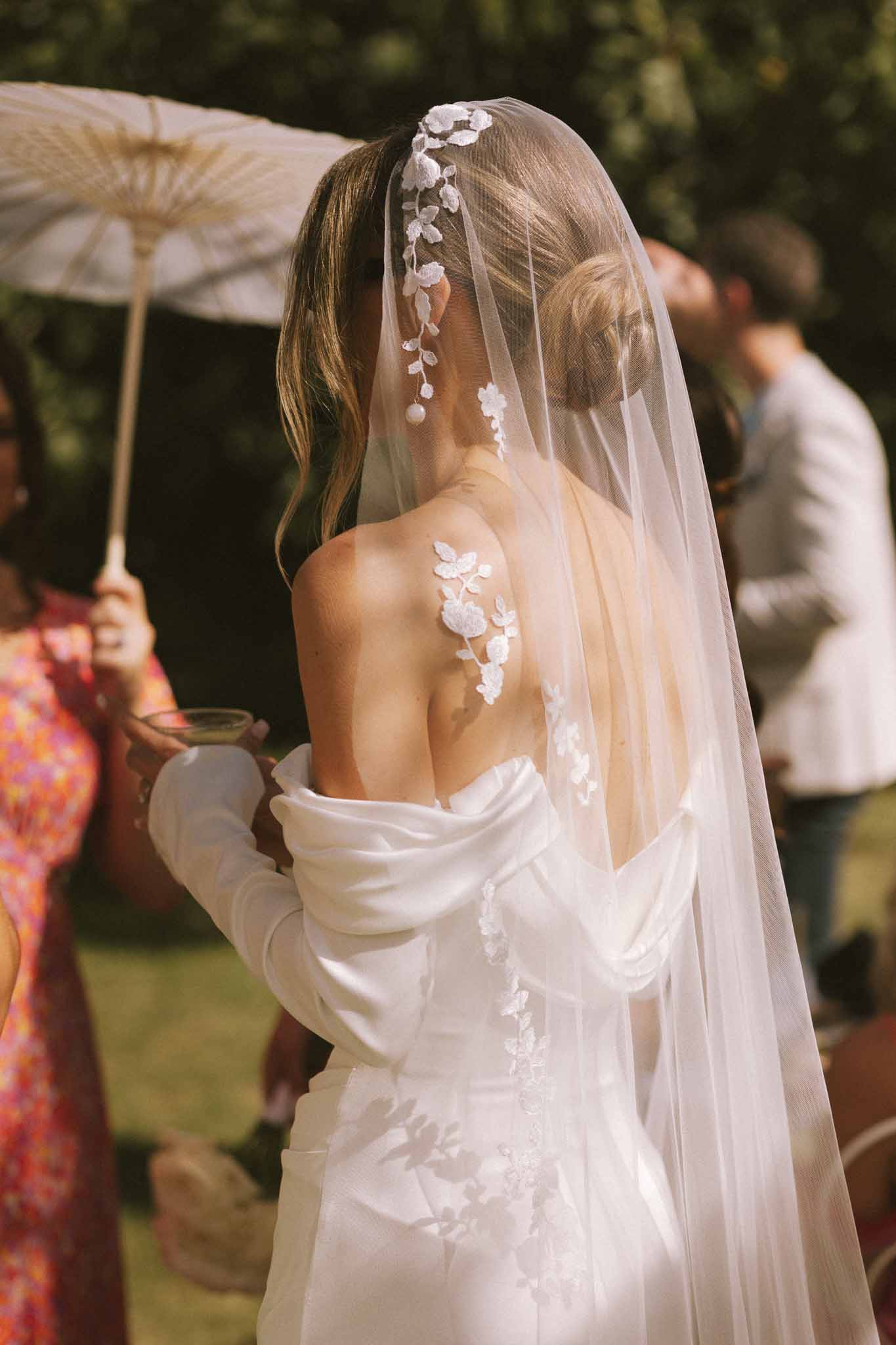 Close-up from behind of bride's floral lace applique back detail and vine-embellished cathedral veil