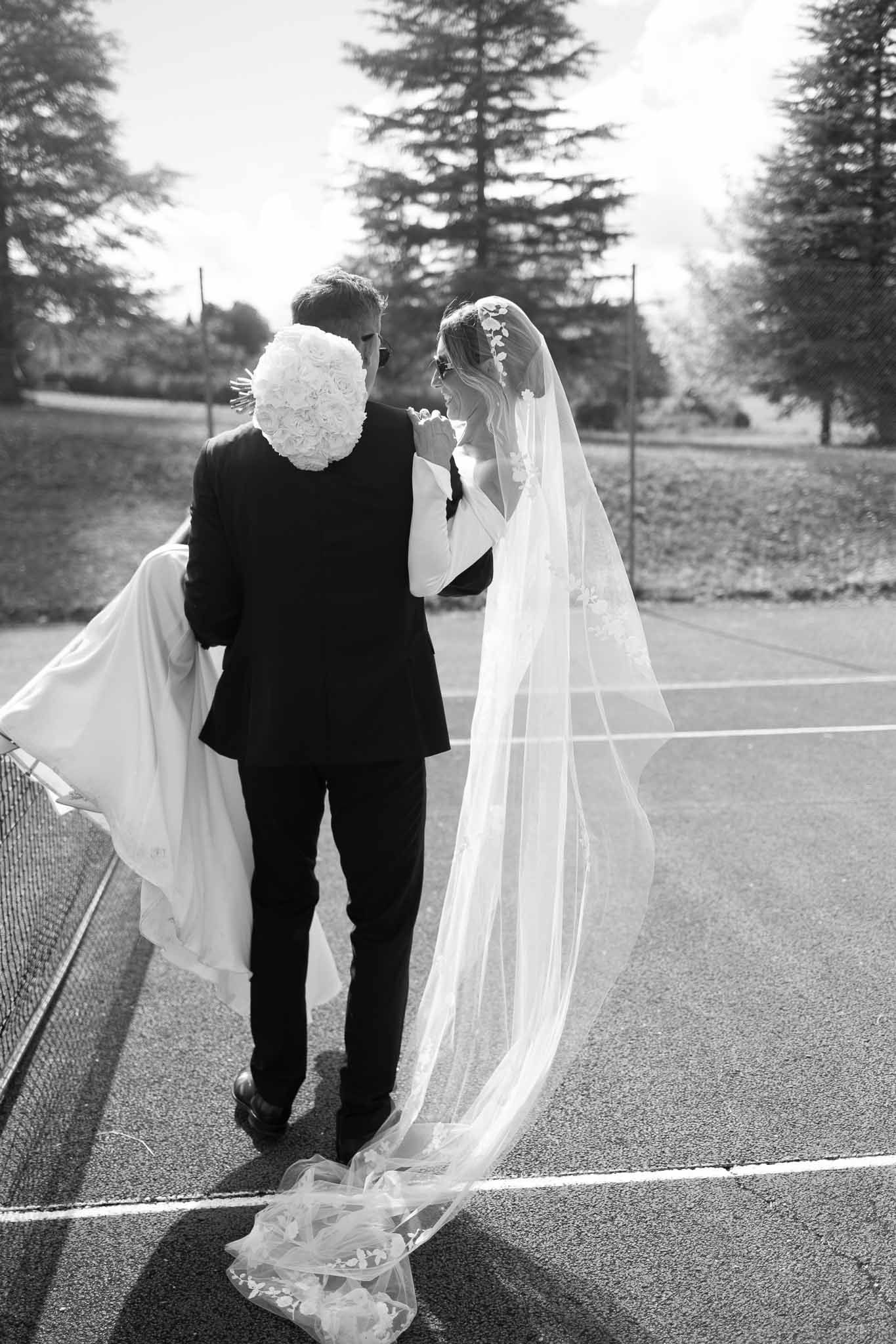 Black and white photo of bride and groom walking hand in hand