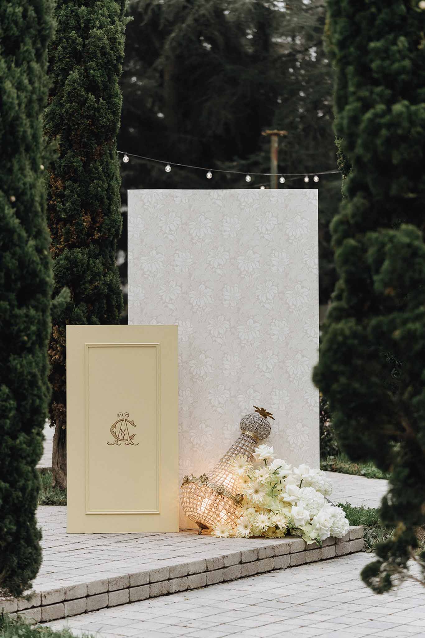 Wedding welcome display with damask panel gold monogram white rose cluster and crystal decanters
