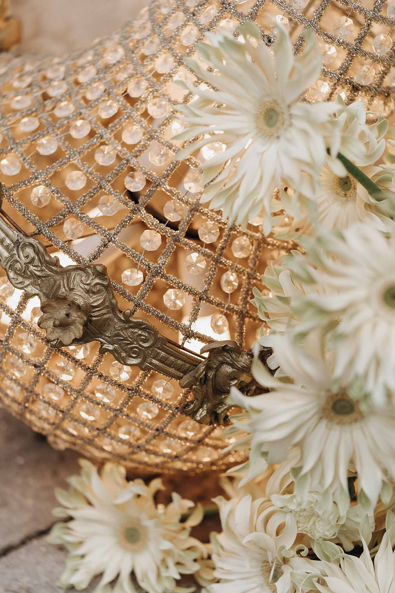 Gold and crystal chandelier centrepiece surrounded by white gerbera daisies and chrysanthemums