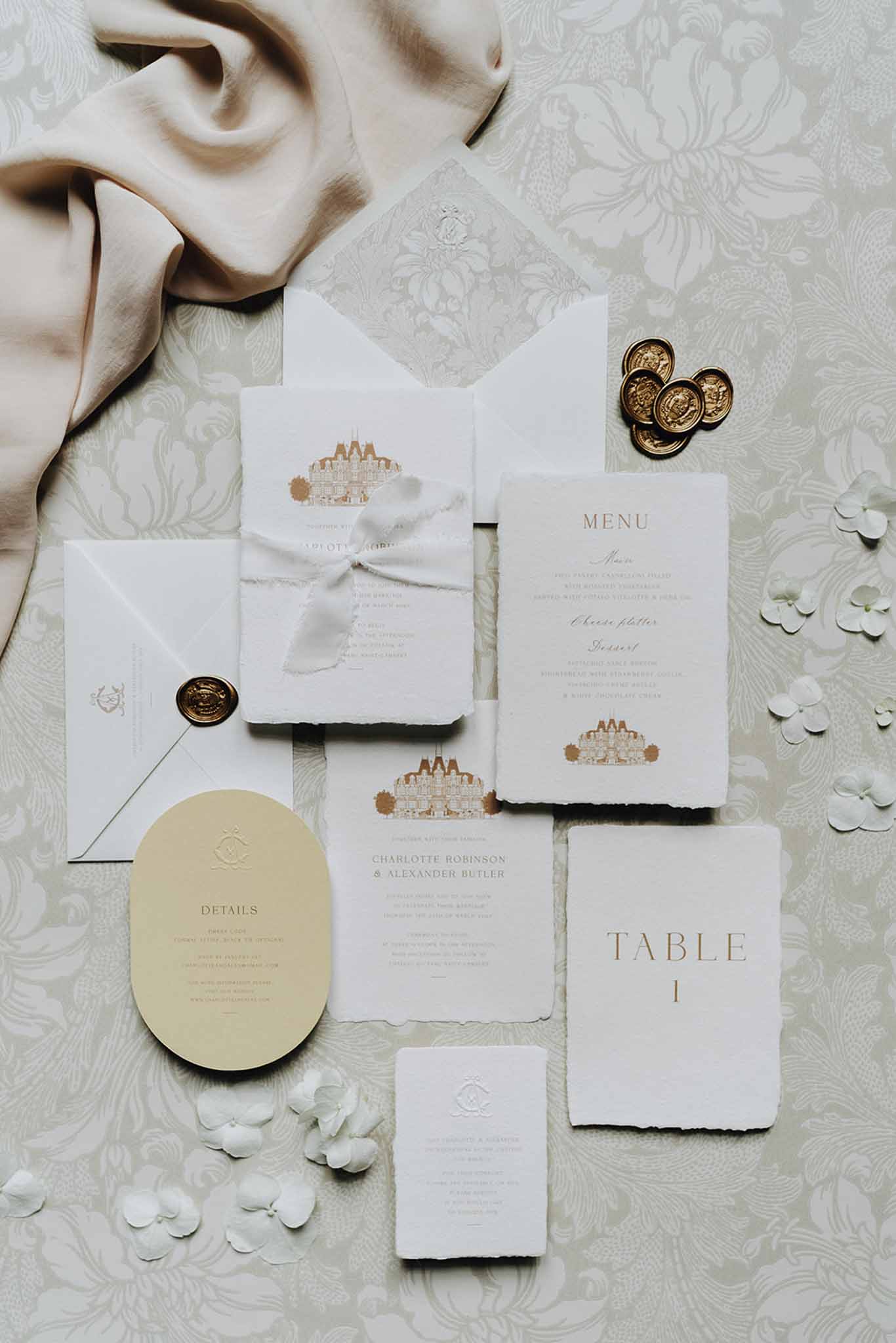 Gold-ink stationery suite with chateau illustration, wax seals, deckled menu, and hydrangea florets