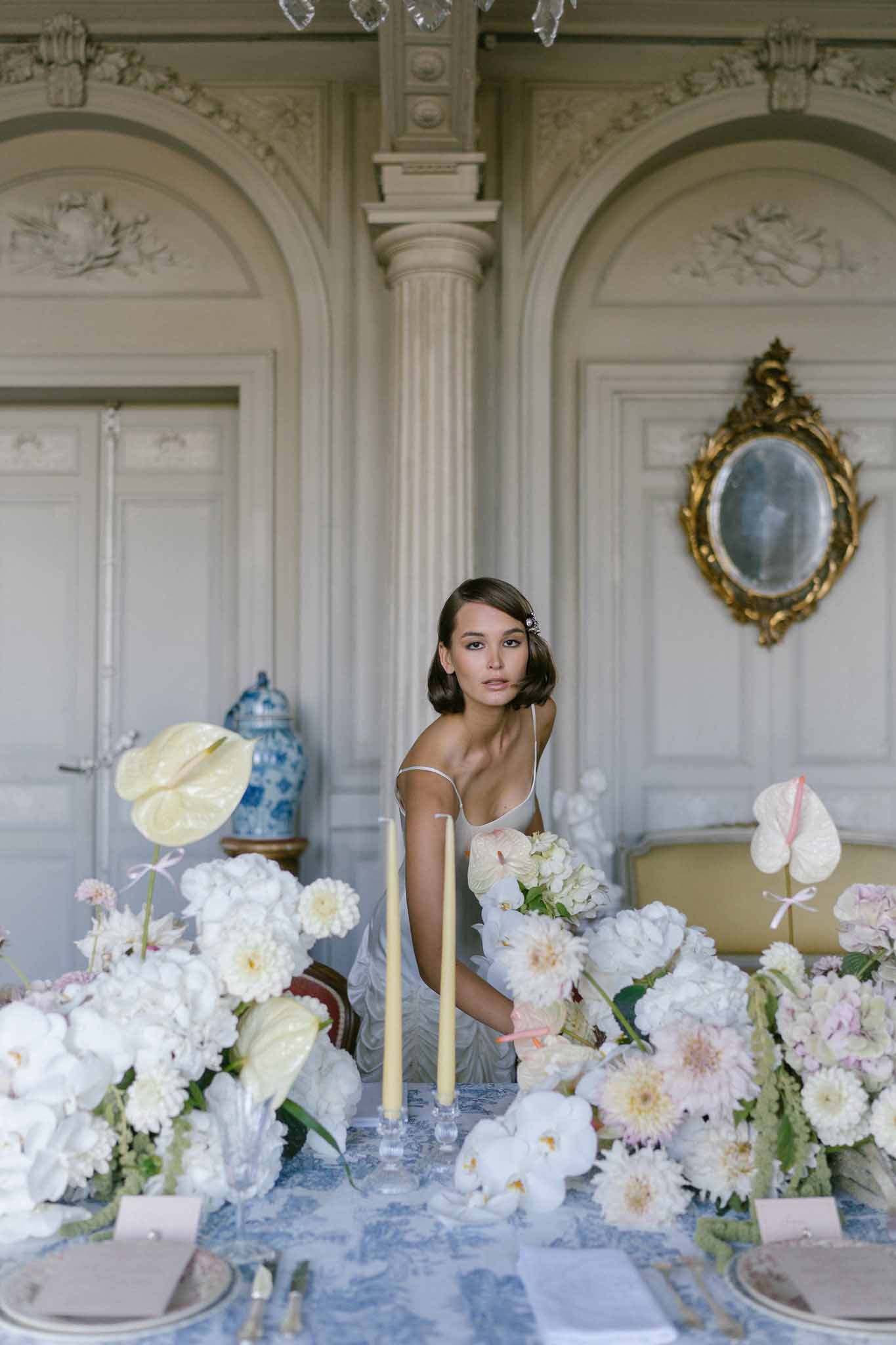 Bride seated at toile de Jouy reception table with white dahlias and blush peonies in chateau salon