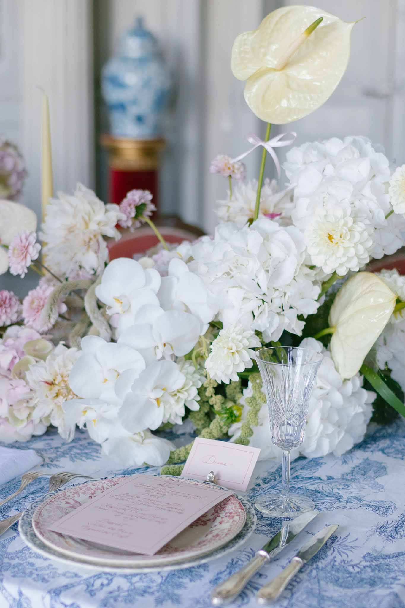 French-styled table setting with toile de Jouy linen, transferware plate, orchid centerpiece, and ginger jar