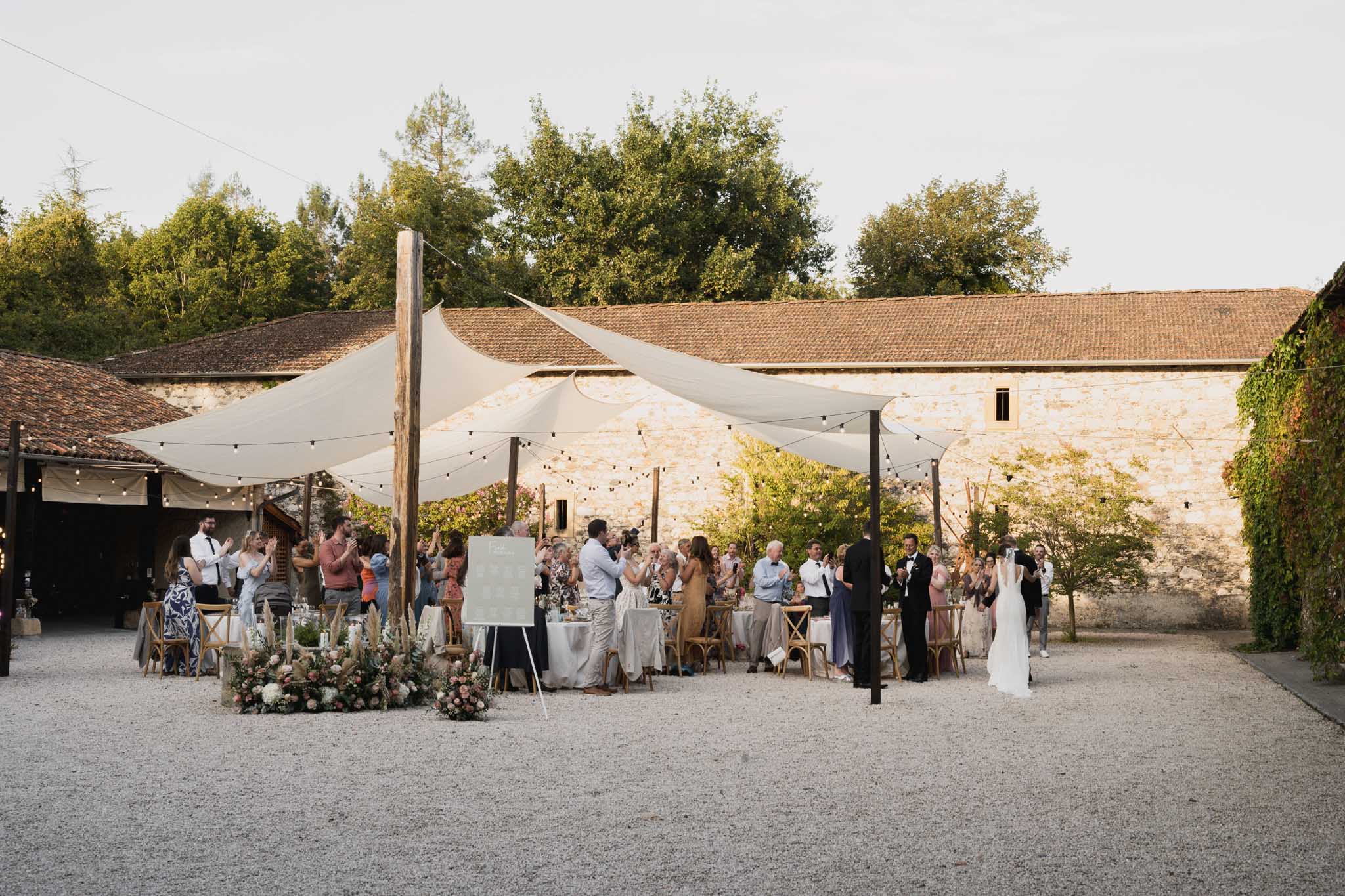 Wedding reception in stone farmyard courtyard with fabric sails and string lights at countryside venue
