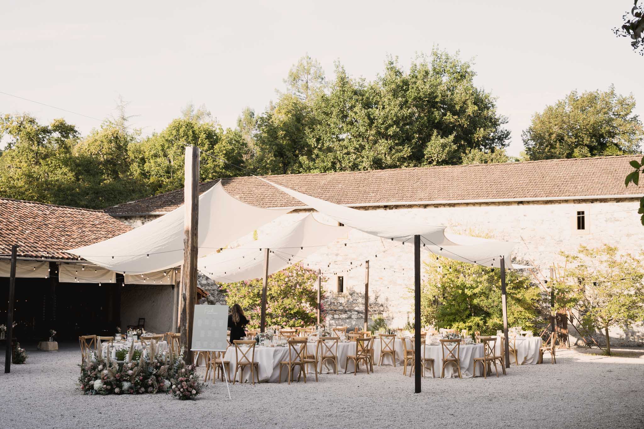Outdoor reception setup in rustic Mediterranean courtyard with cream stone buildings and terracotta roofs