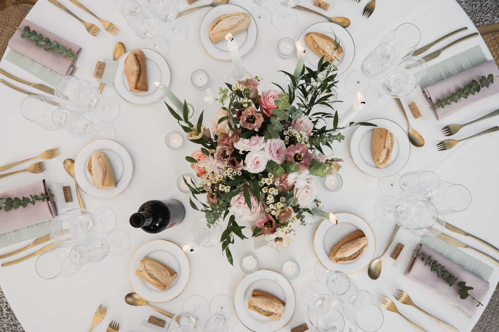 Overhead flat-lay of elegant reception table setting with floral centerpiece and gold accents