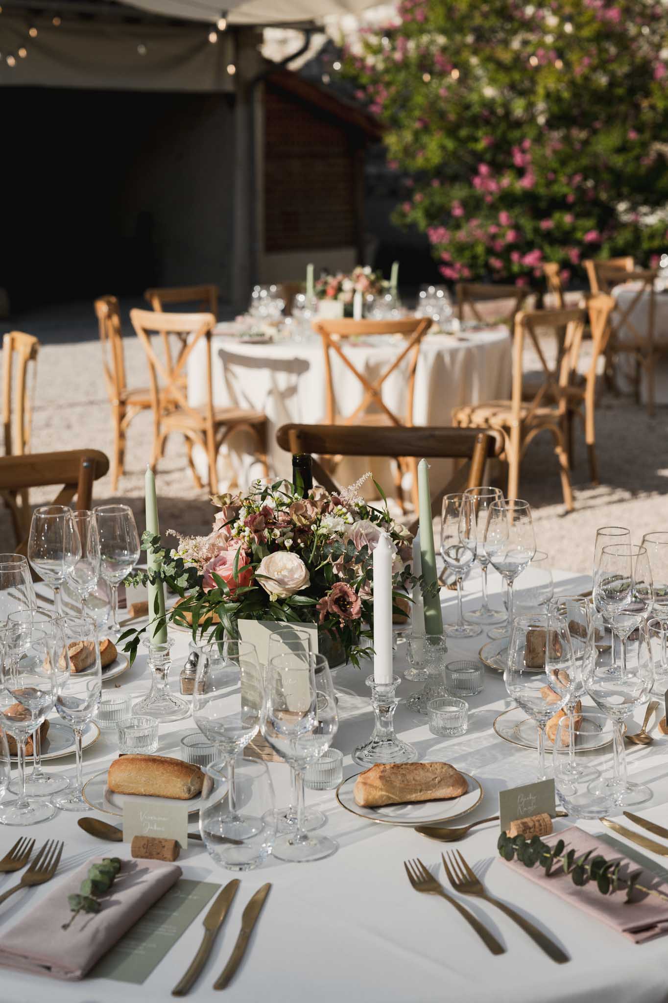 Reception tablescape with dusty rose florals and brass flatware at outdoor courtyard venue