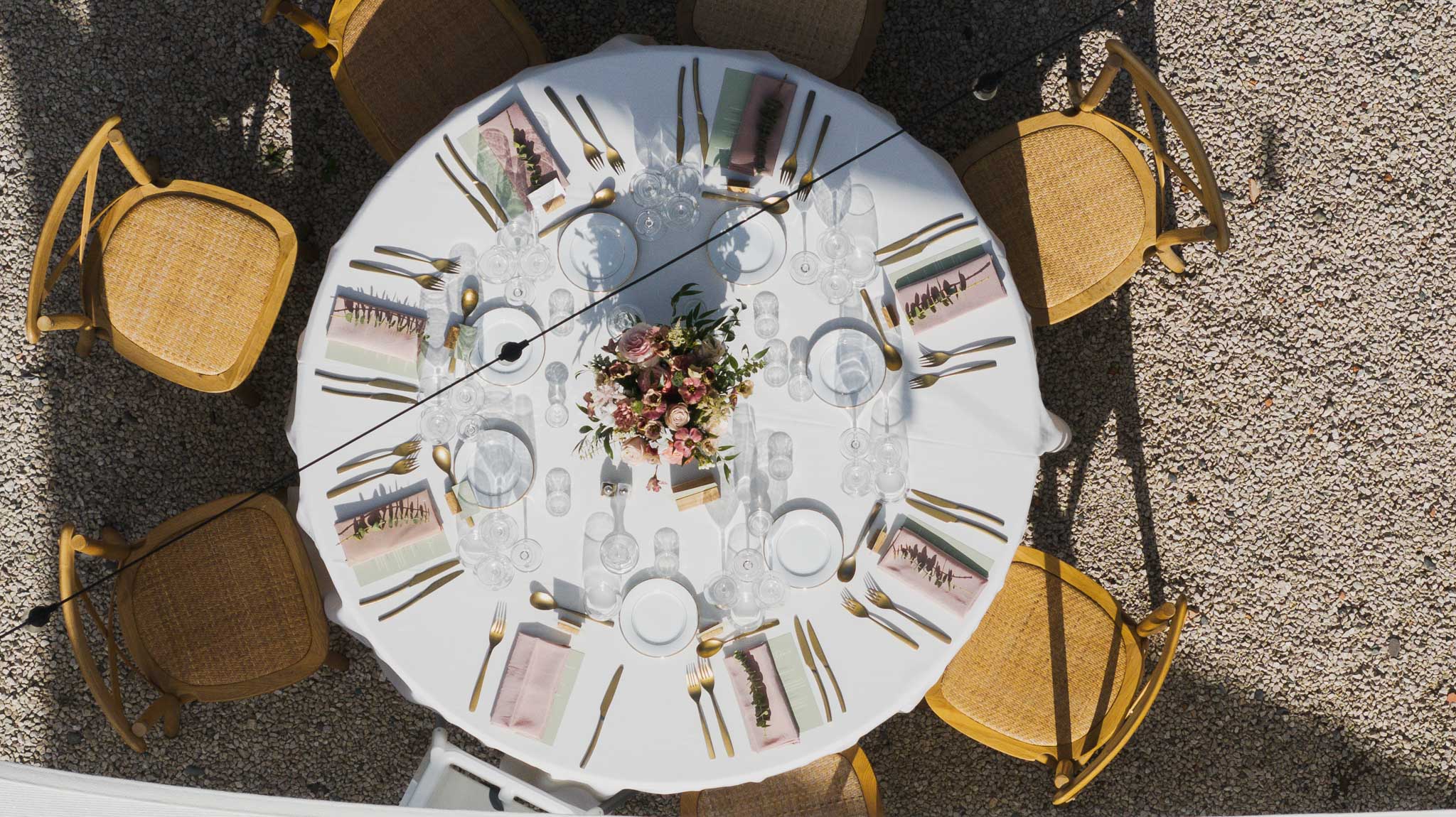 Overhead view of round reception table with yellow chairs and floral centerpiece at outdoor wedding venue