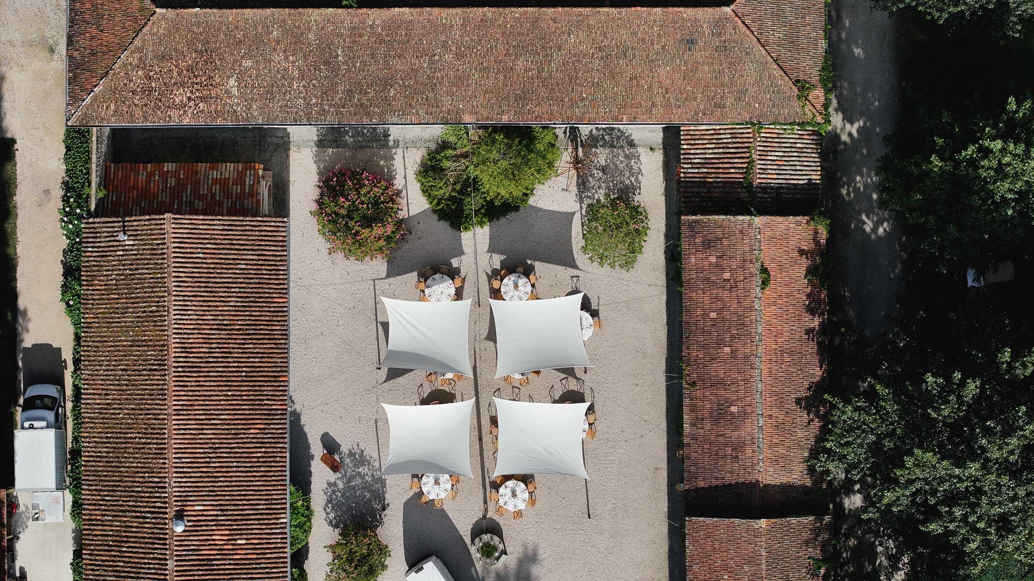 Aerial view of courtyard reception setup with round tables and ivy-covered brick walls