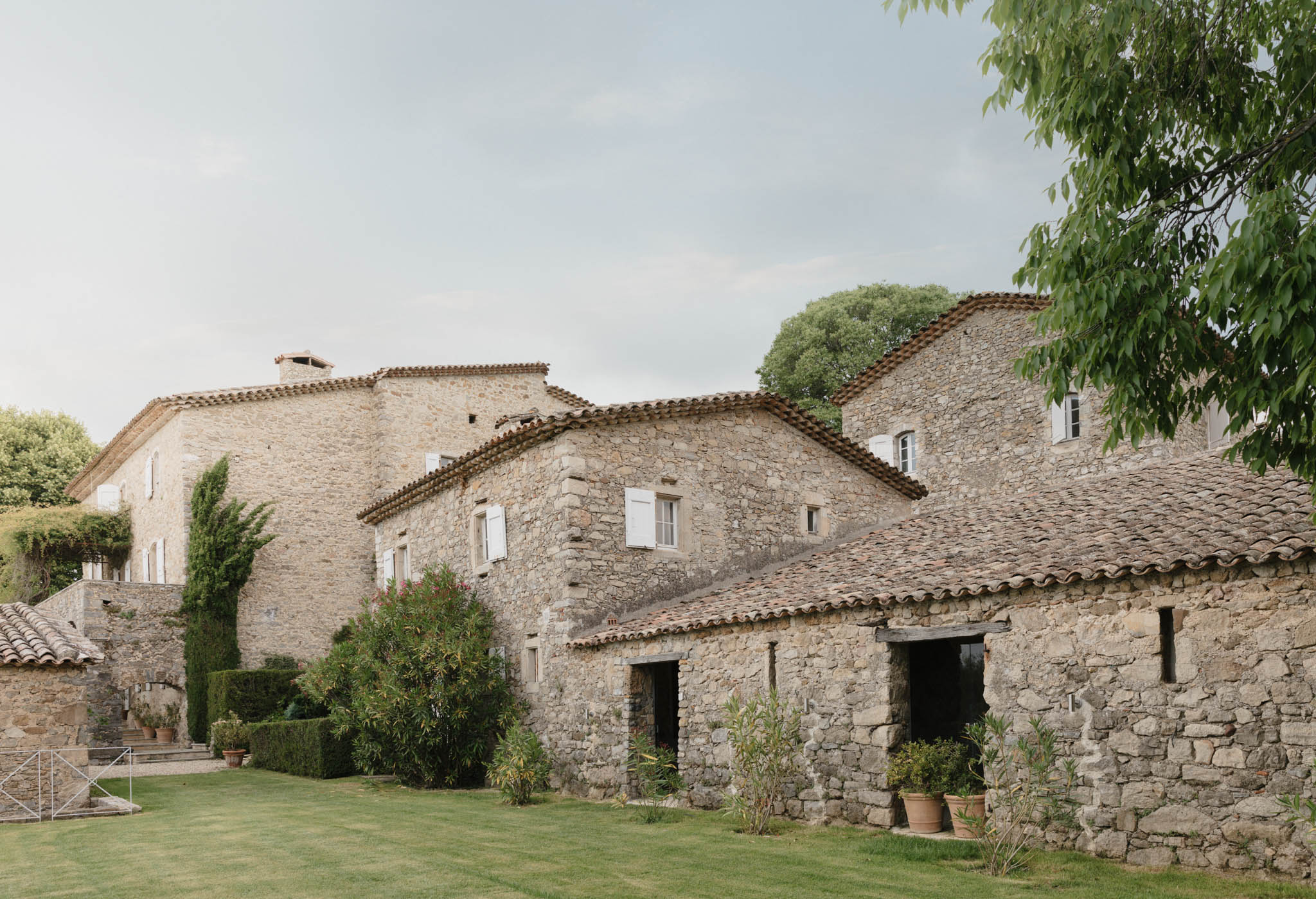 Provencal stone mas farmhouse complex with terracotta roofs, limestone facades, manicured lawn, and cypress trees