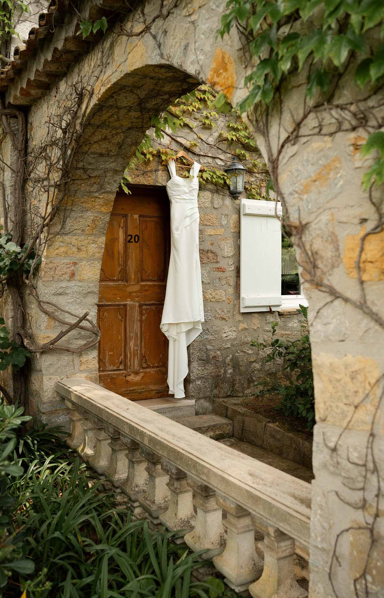 White wedding dress hanging from stone archway doorway of historic building exterior
