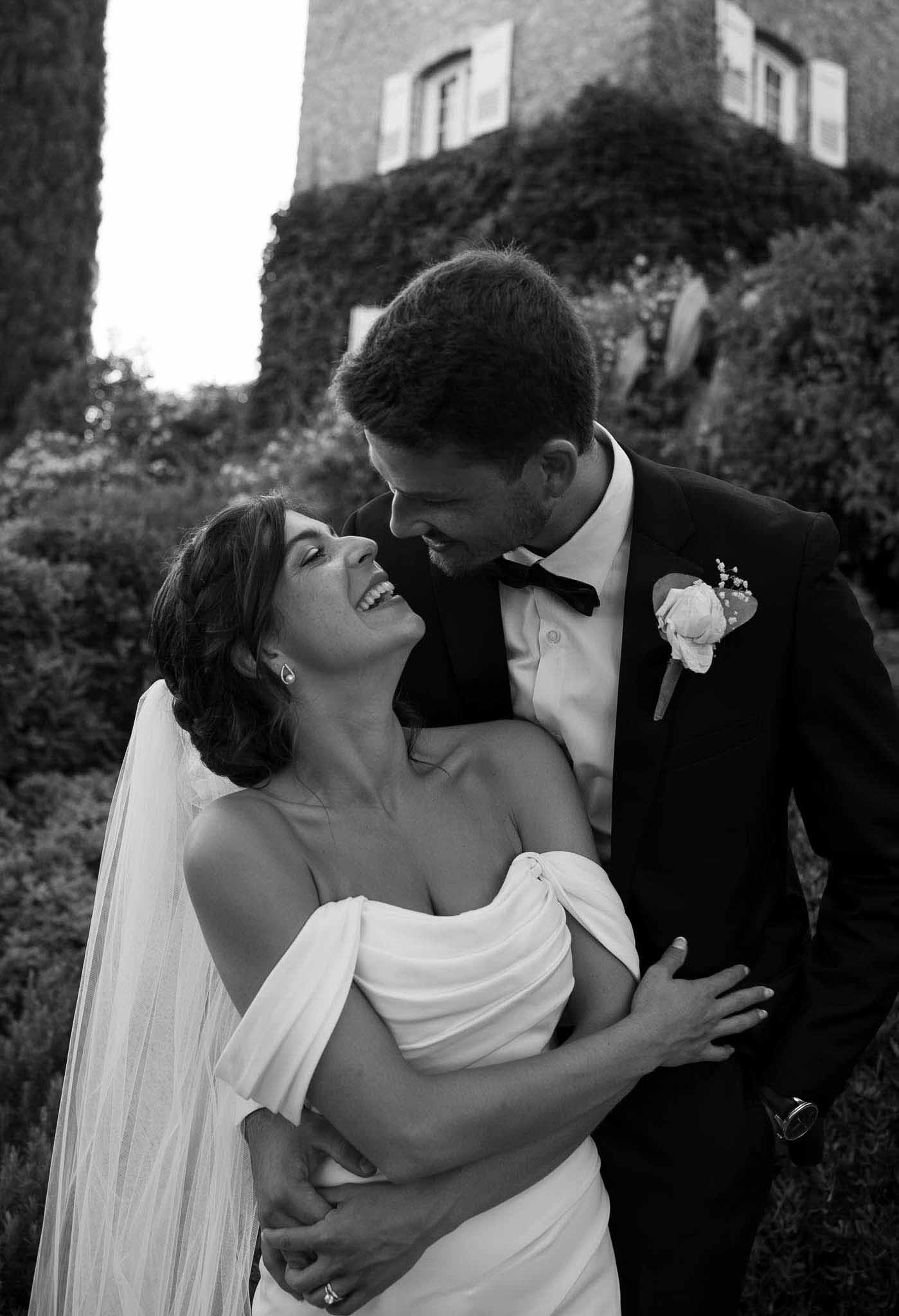Black and white couple laughing and embracing with ivy-covered chateau tower in background