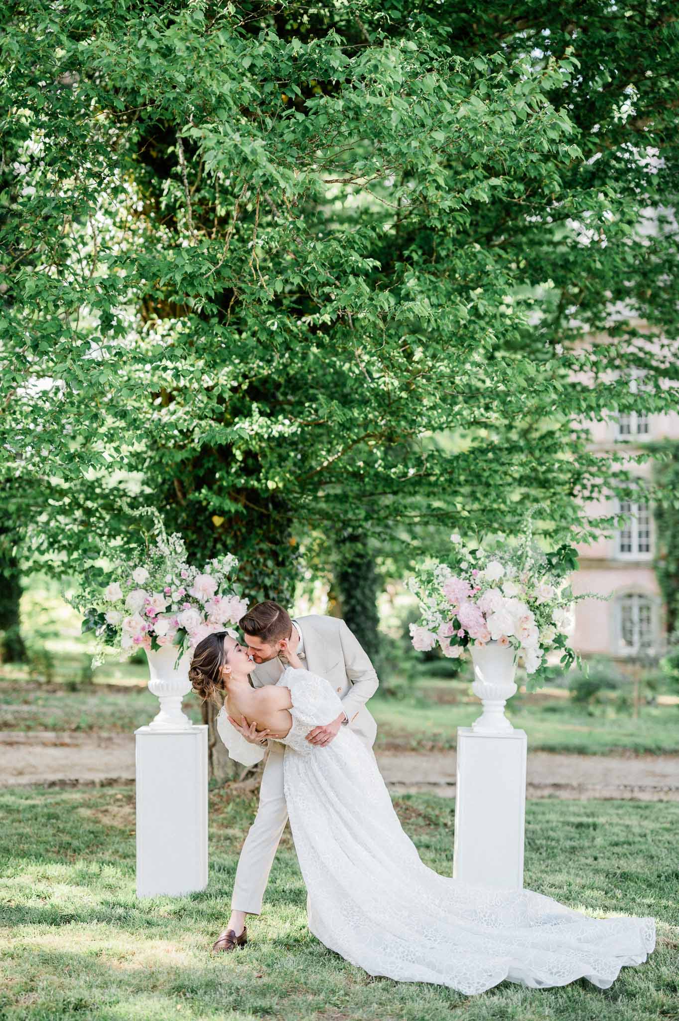 Bride and groom romantic kiss portrait in garden pergola with peony arrangements