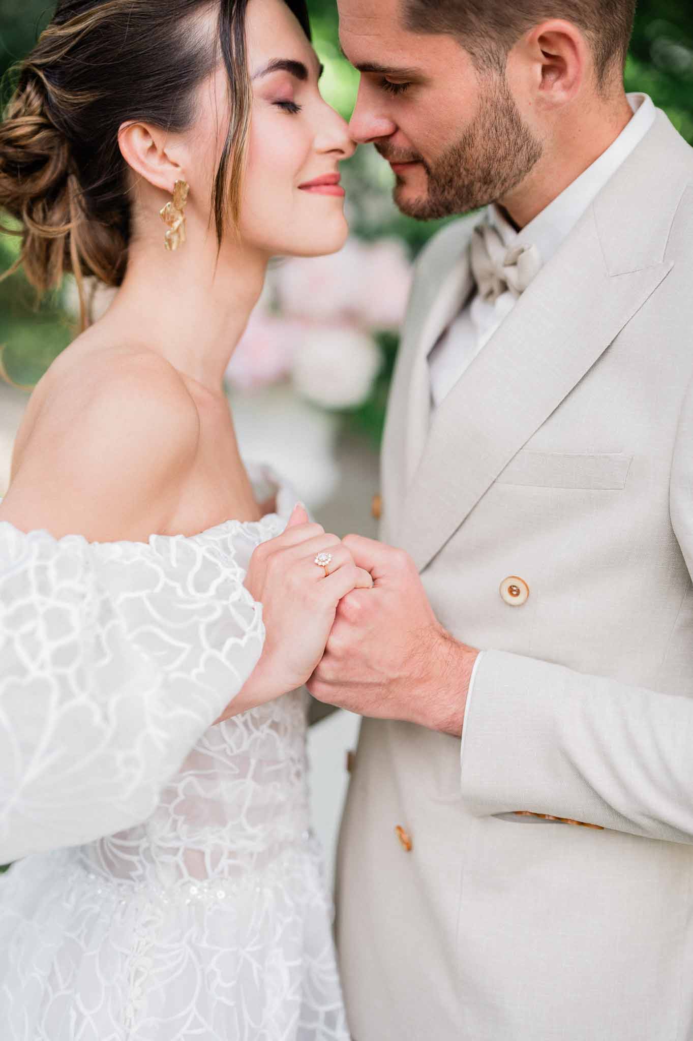 Bride and groom intimate portrait showing wedding dress details and jewelry in outdoor garden setting