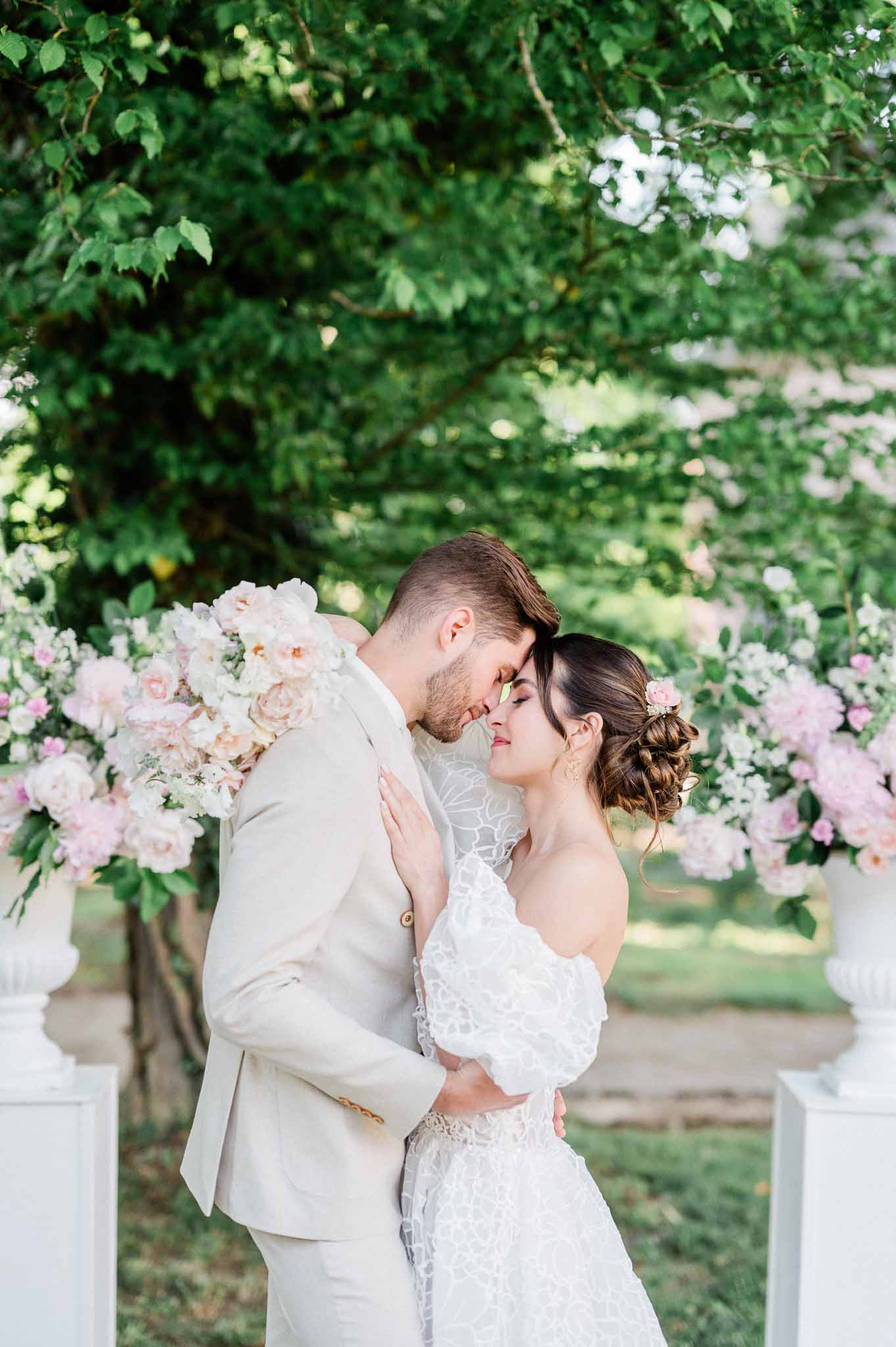 Bride and groom portrait under flowering archway in garden setting
