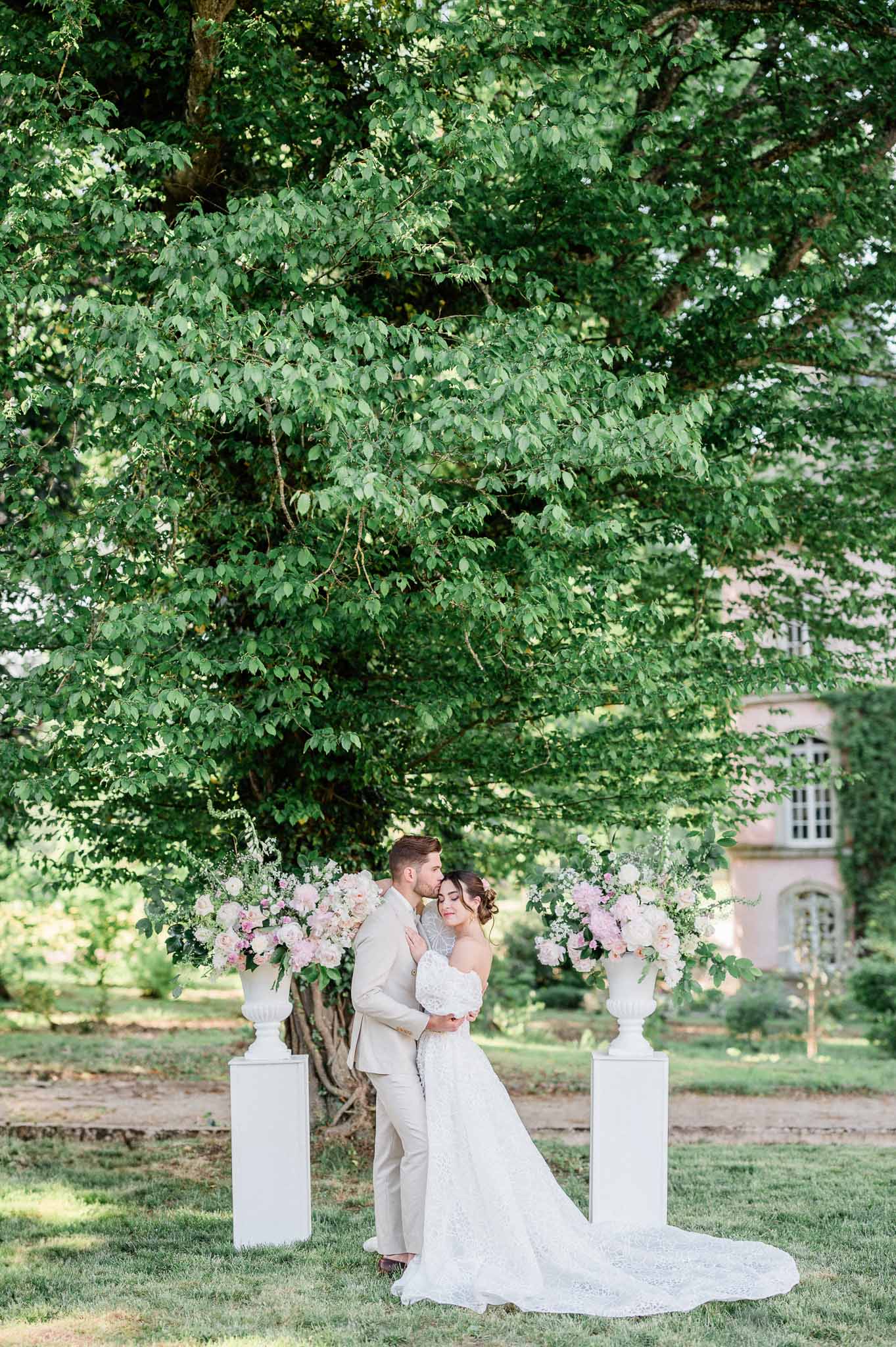 Bride and groom portrait in garden setting with floral arrangements at chateau venue