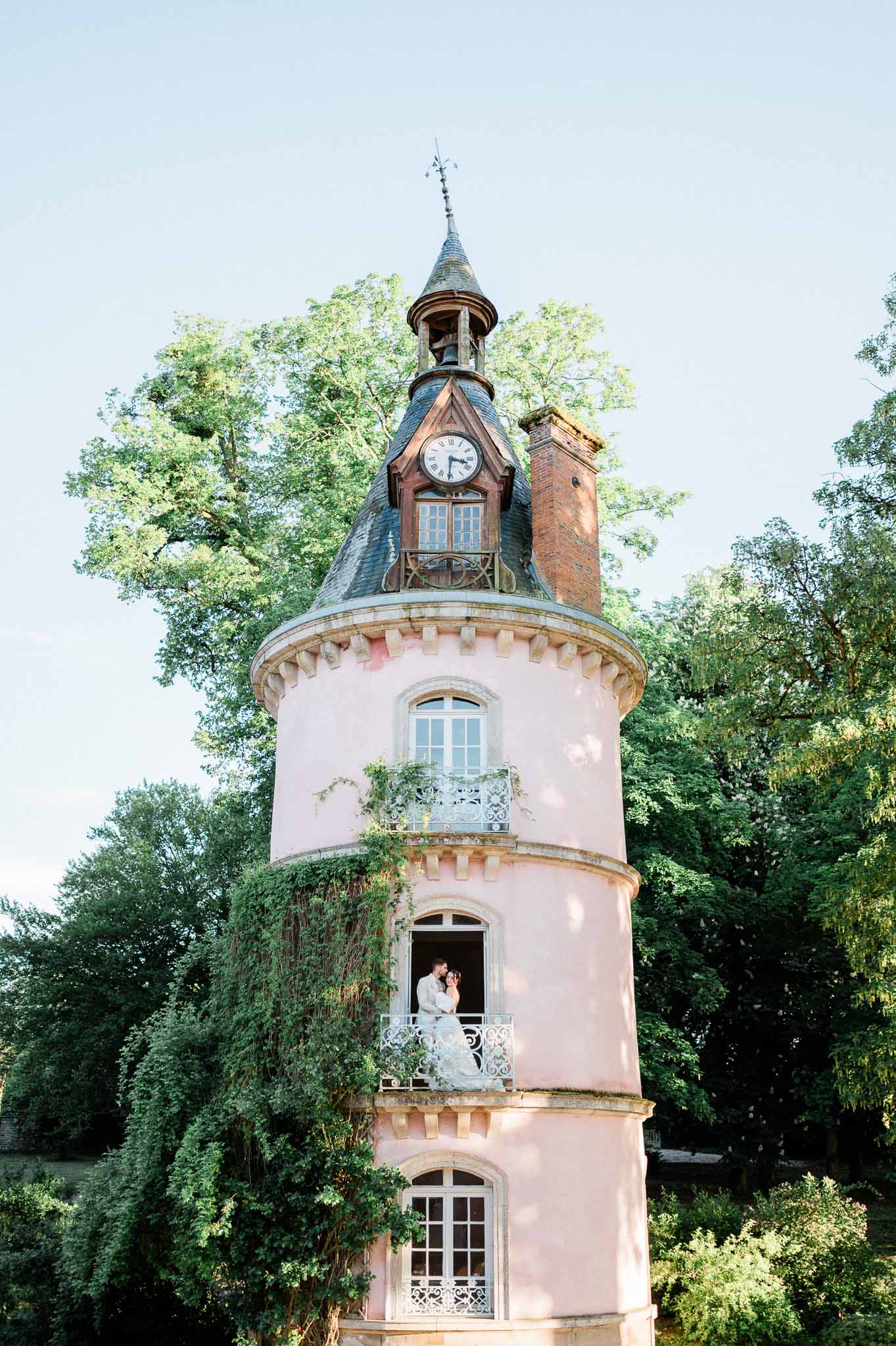 Bride and groom on pink tower balcony at romantic wedding venue